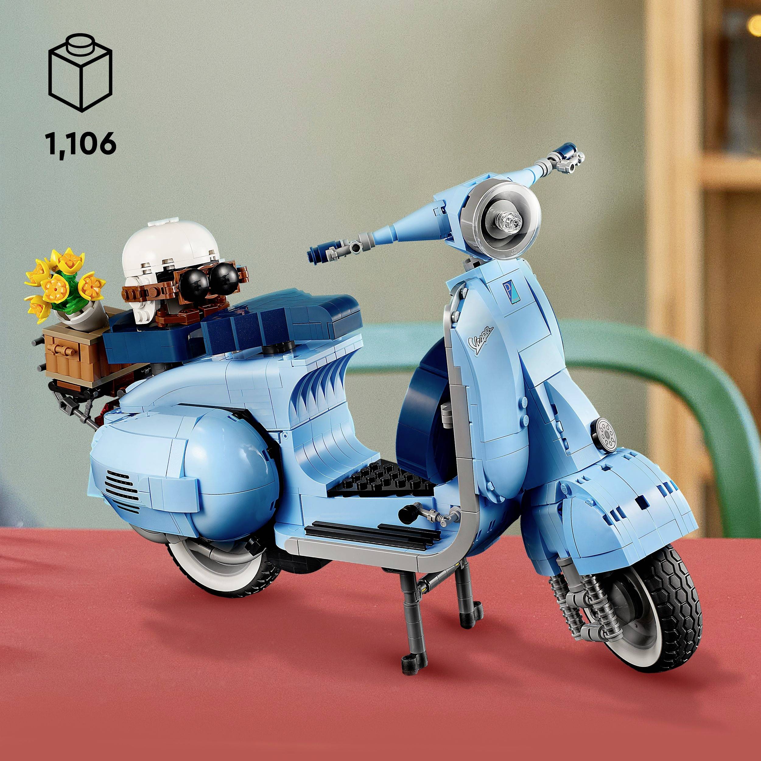 Blå modell av en scooter gjord av byggstenar på ett bord. En blombukett är placerad baktill. Antal i förpackningen: 1.106.