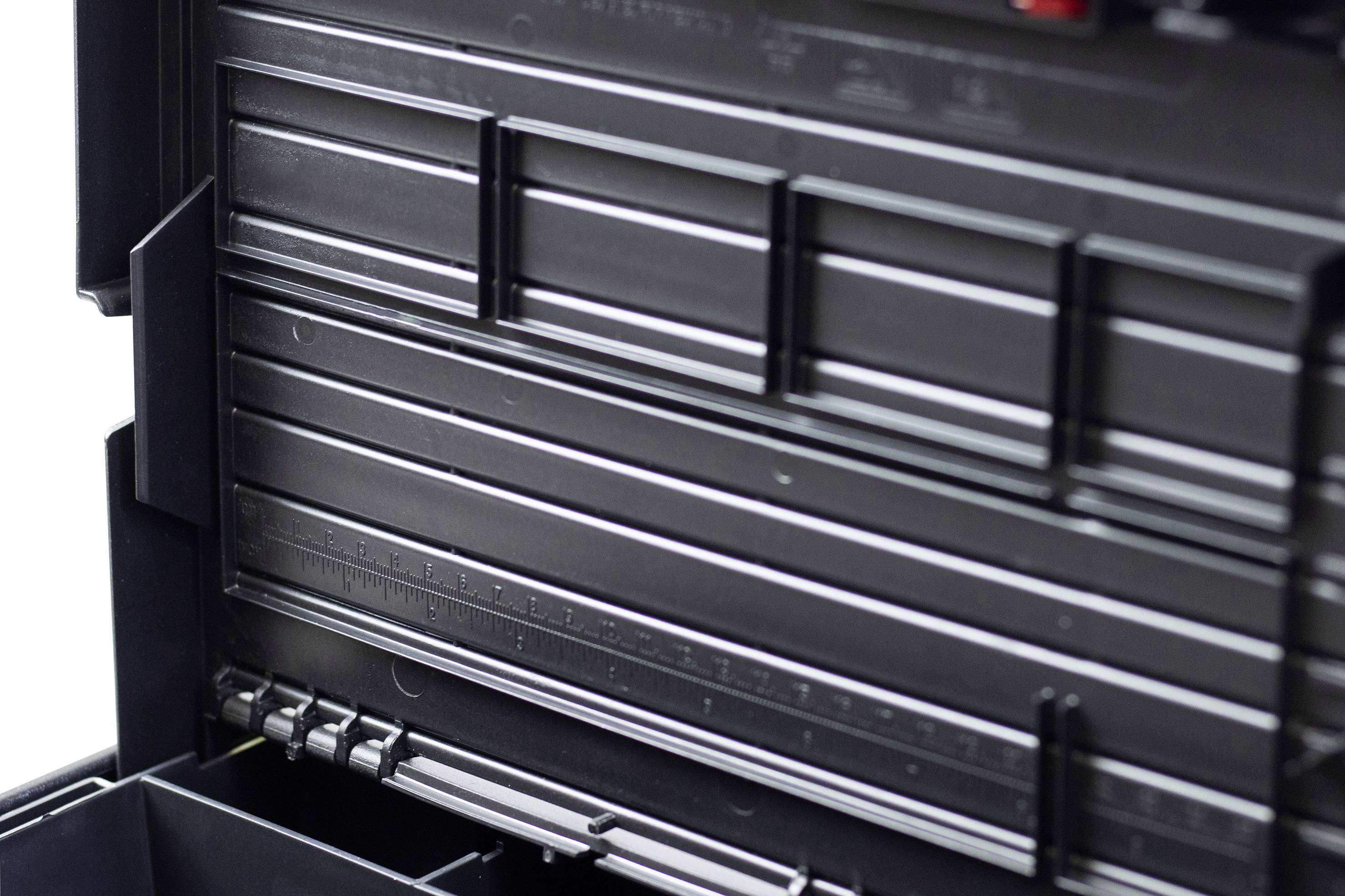 En öppnad verktygslåda med flera fack och lådor som är tomma. Lådan är svart med fina räfflor.