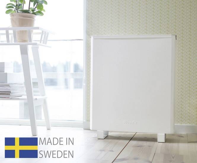 En vit luftrenare från 'Blueair' står i ett ljust rum bredvid ett bord med en växt. Nere till vänster: 'MADE IN SWEDEN'.