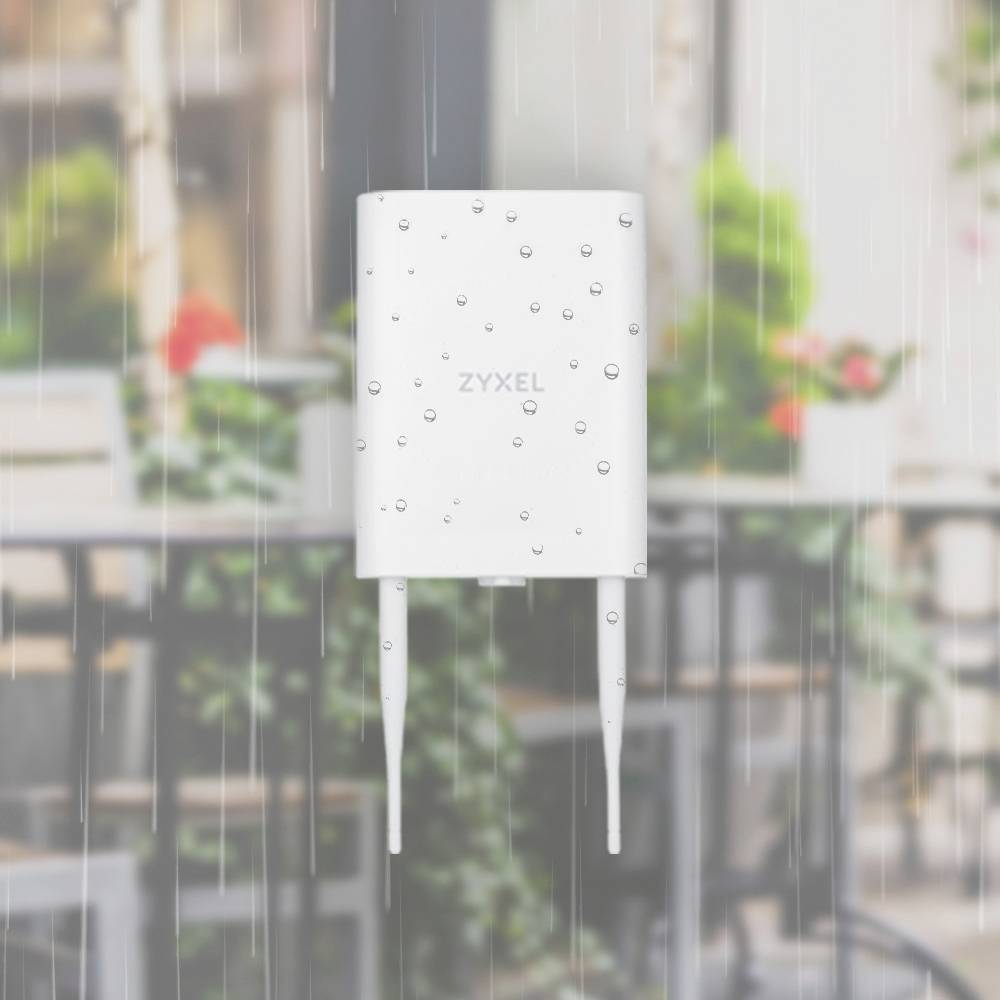 En vit router från Zyxel med två antenner under regn, placerad framför en oskarp bakgrund med trädgårdsmöbler och växter.