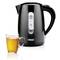 En svart elektrisk vattenkokare med synlig vattennivåindikator står bredvid en kopp med ljust te på en vit bakgrund.