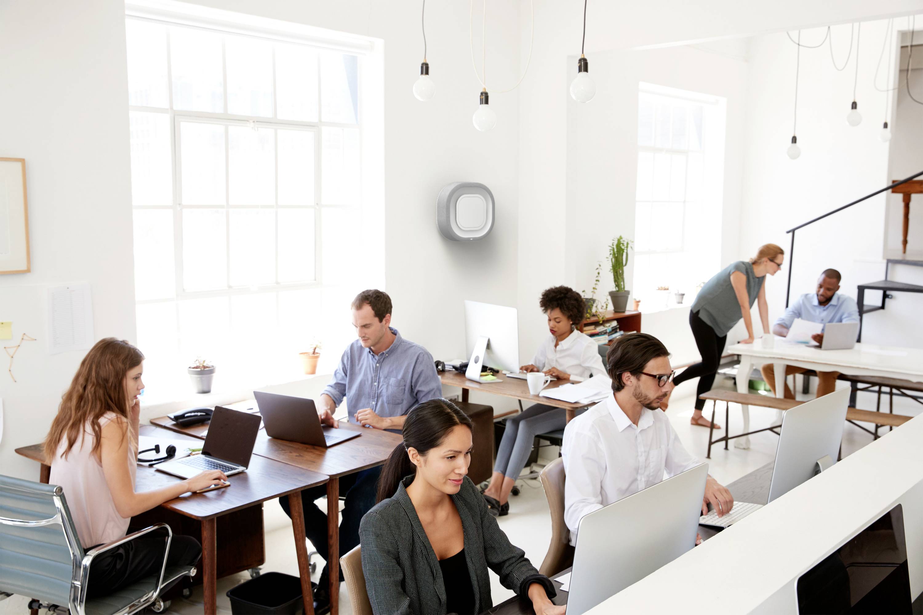 En grupp personer arbetar i ett modernt kontor med bärbara datorer och papper. Ljus och öppen rumsdesign främjar produktivitet.