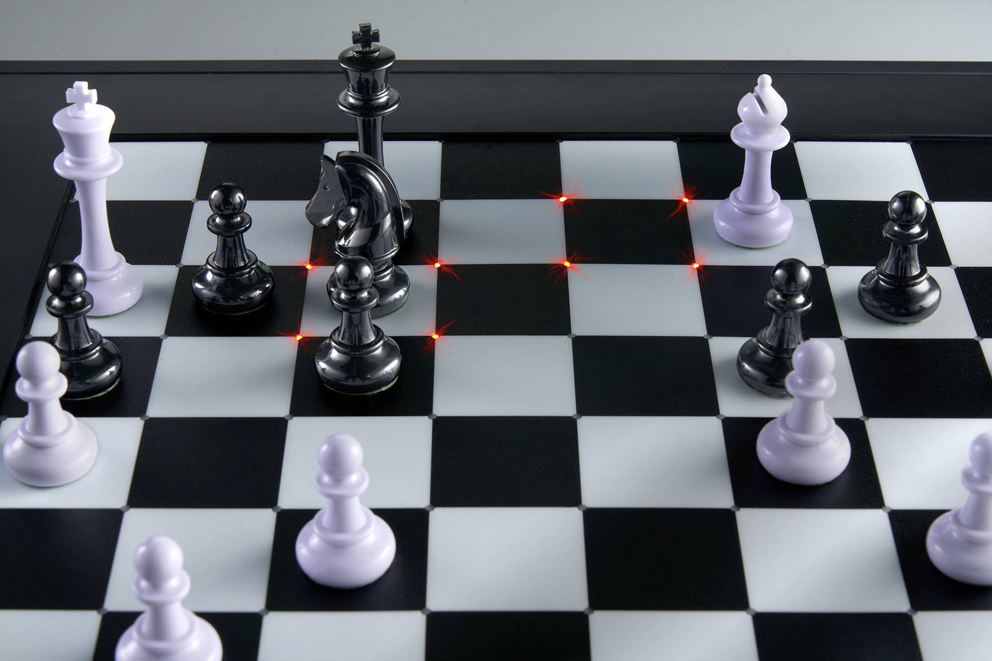 Schackbräde med vita och svarta pjäser; Kungen hotad av röda linjer. Strategisk spelsituation.