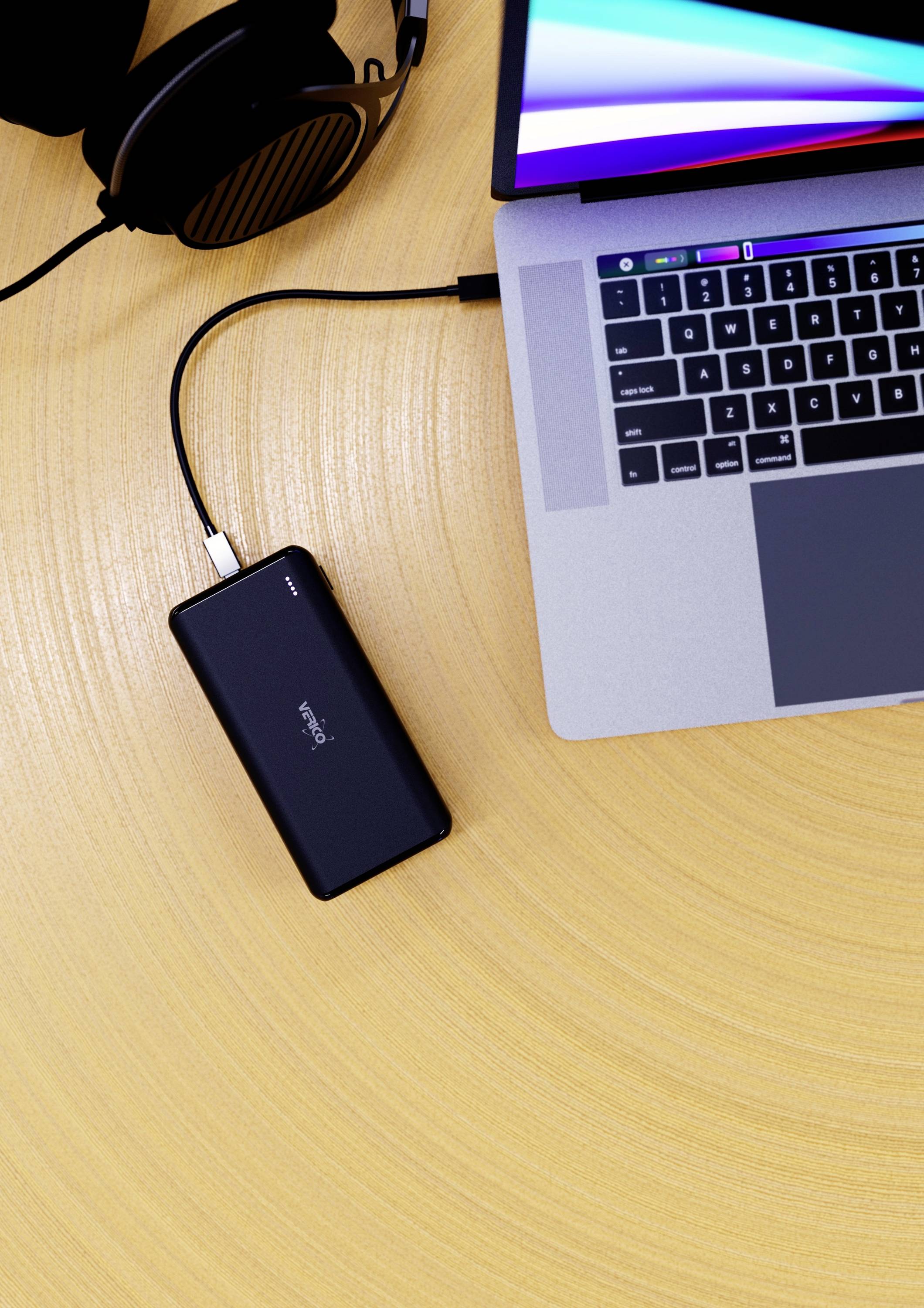 Bärbar dator på ett träbord, ansluten till en svart powerbank och hörlurar. Datorskärmen är tänd och visar färgglada ränder.