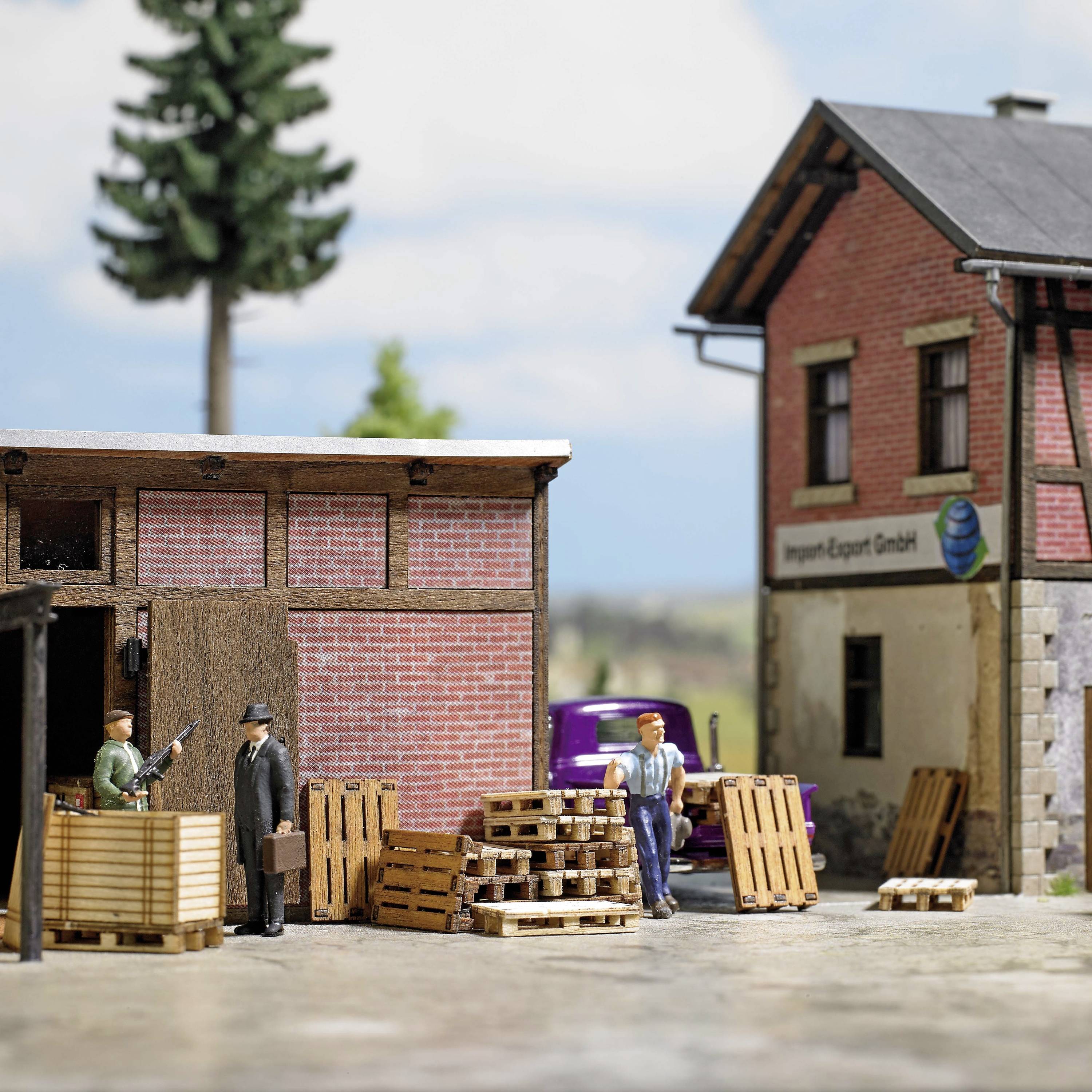En miniatyrscen visar arbetare som lastar och lossar pallar framför ett varulager med skylten 'Import-Export AB'.