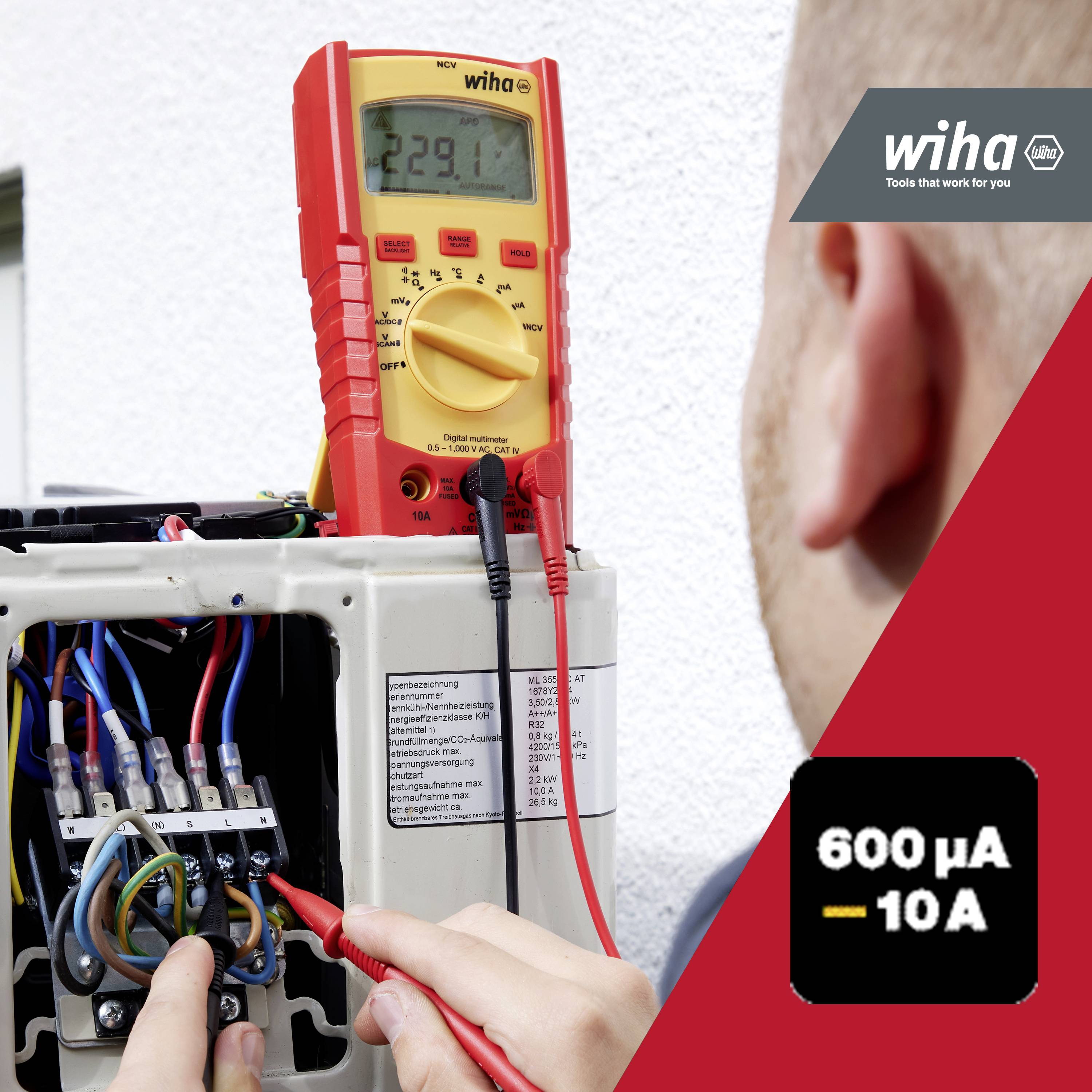 En multimeter mäter spänningen i ett öppet elektriskt kopplingsskåp. En person håller mätspetsarna mot kontakterna.