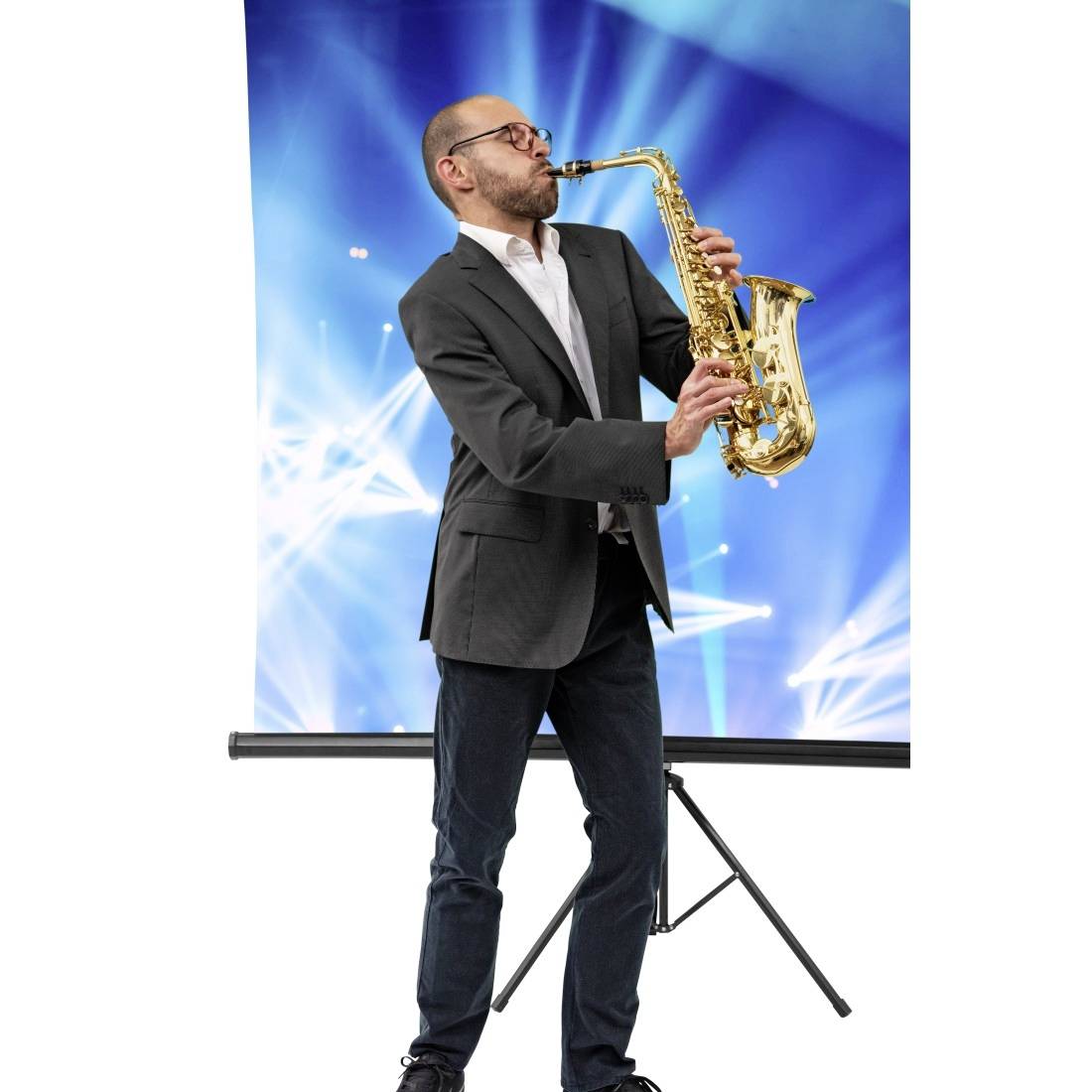 En man i kostym spelar saxofon framför en bakgrund med blå ljus och strålar.