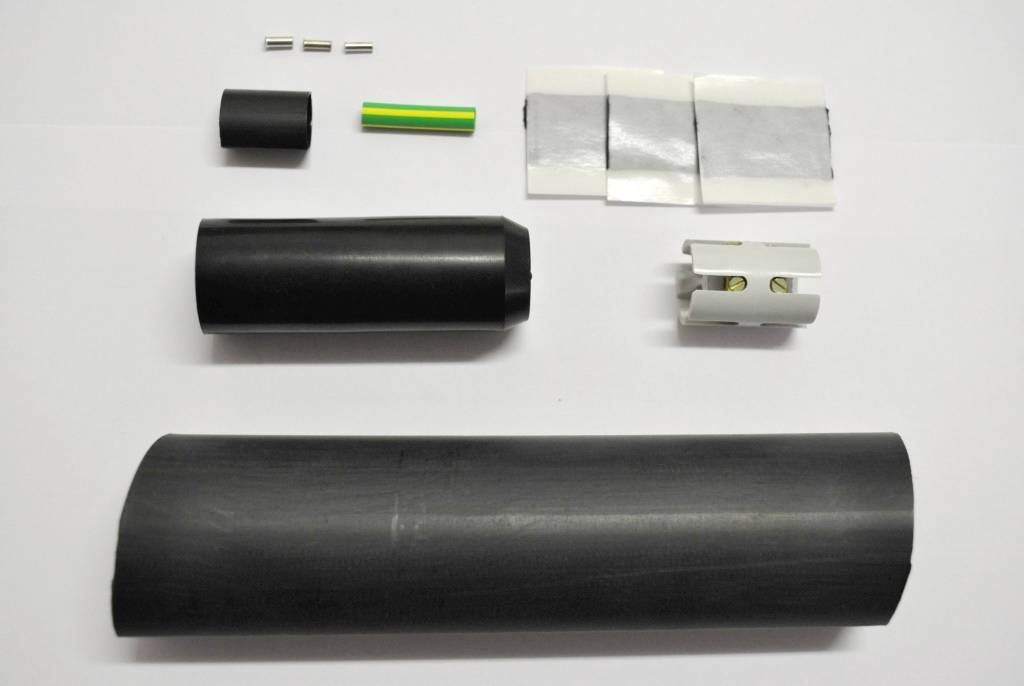 En kabelanslutningssats med krympslang, en kontakt, metallstift och ett grönt rör som används för isolering.