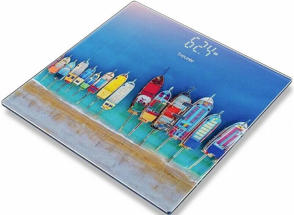 Färgglada strandhus på en personvåg. Displayen visar '62,4 kg'.