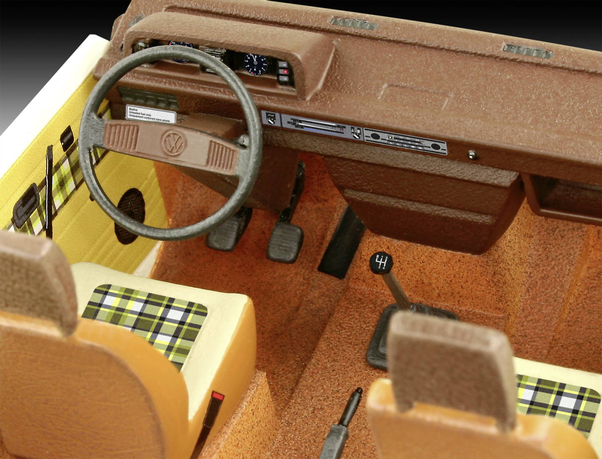Interiör från en miniatyrmodellbils cockpit med ratt, instrumentbräda och rutiga säten i jordnära färger.