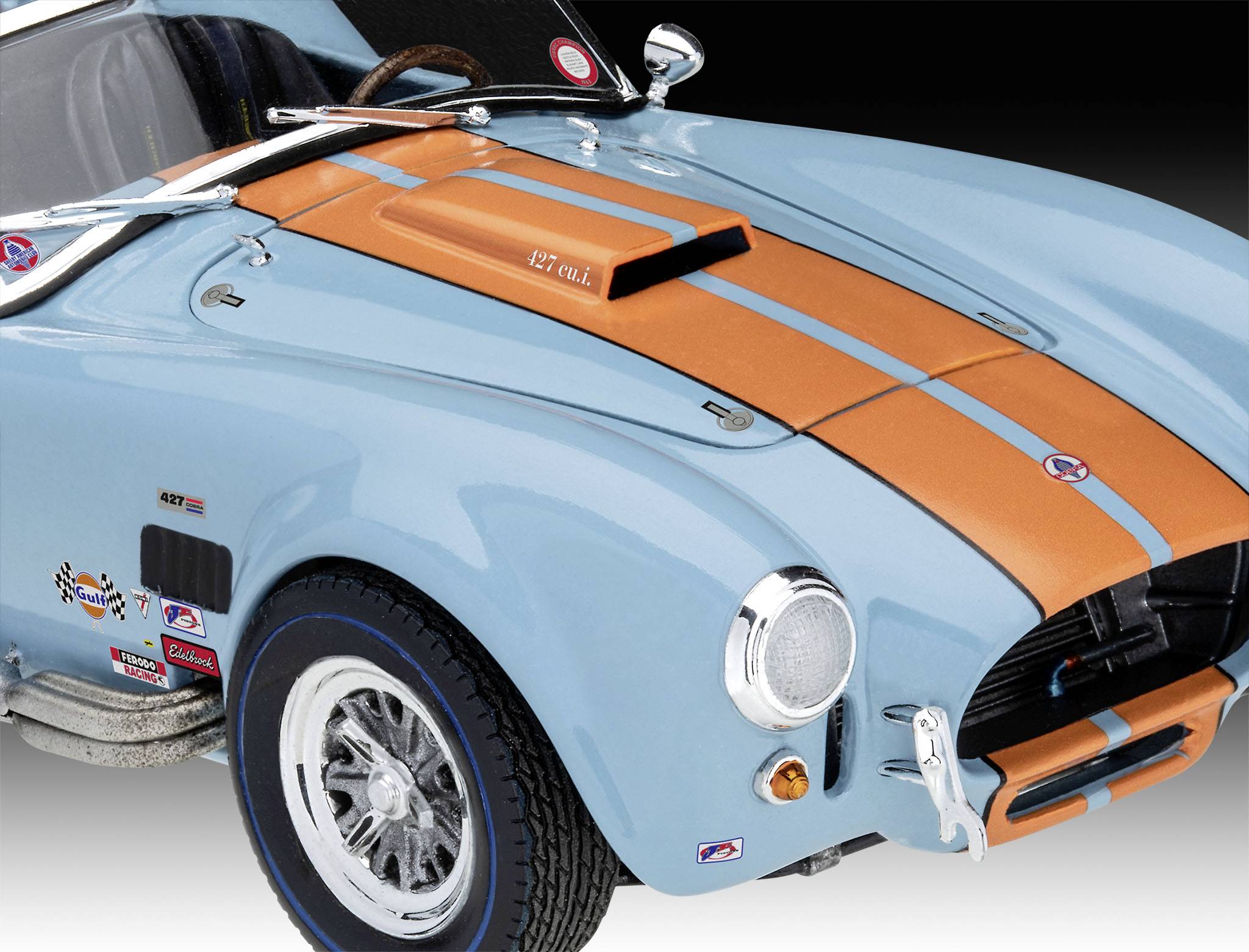 En ljusblå veteranbil med orangea racerränder. Iögonfallande luftintag på motorhuven och en förkromad stötfångare.