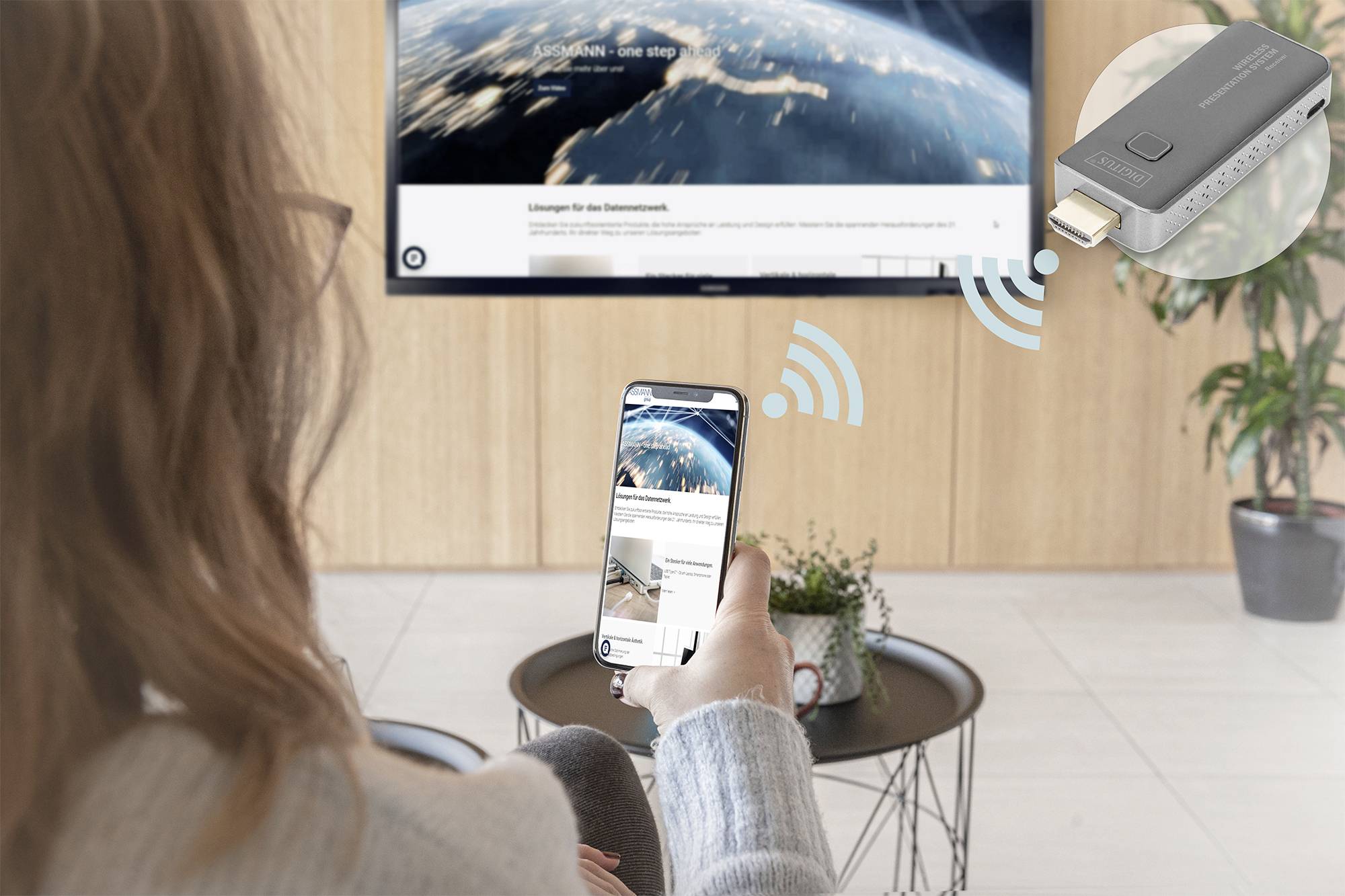 En person med en smartphone speglar innehåll trådlöst på en TV. En HDMI-sticka framstår som förbindelsemedel.