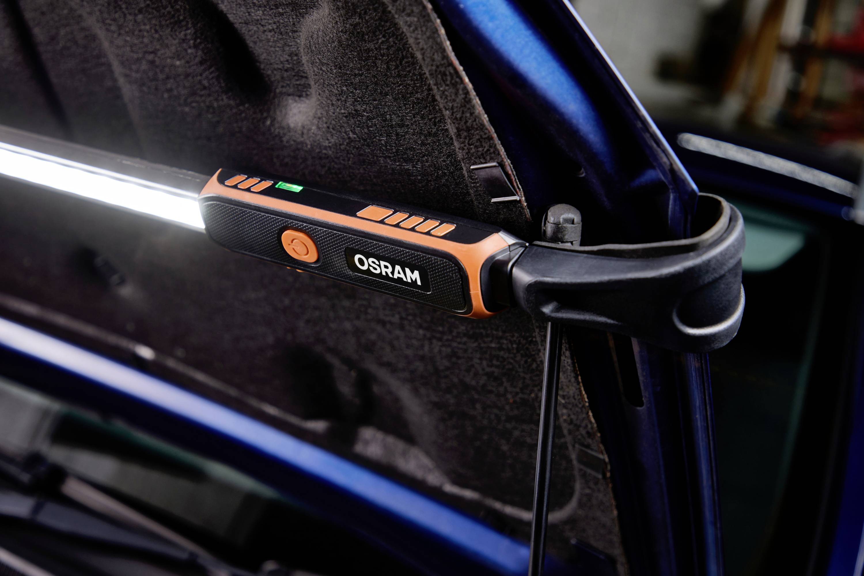 En arbetslampa från Osram är fäst vid den öppnade motorhuven på en bil för att belysa motorutrymmet.