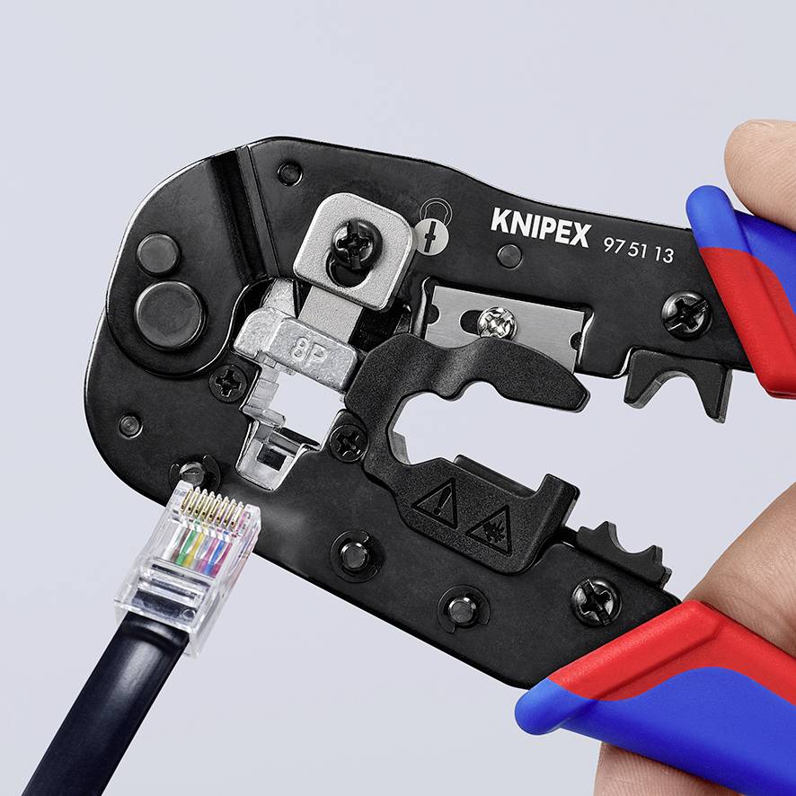Ett krympverktyg pressar en RJ45-kontakt på en Ethernetkabel. Verktyget är svart med röda och blå handtag.