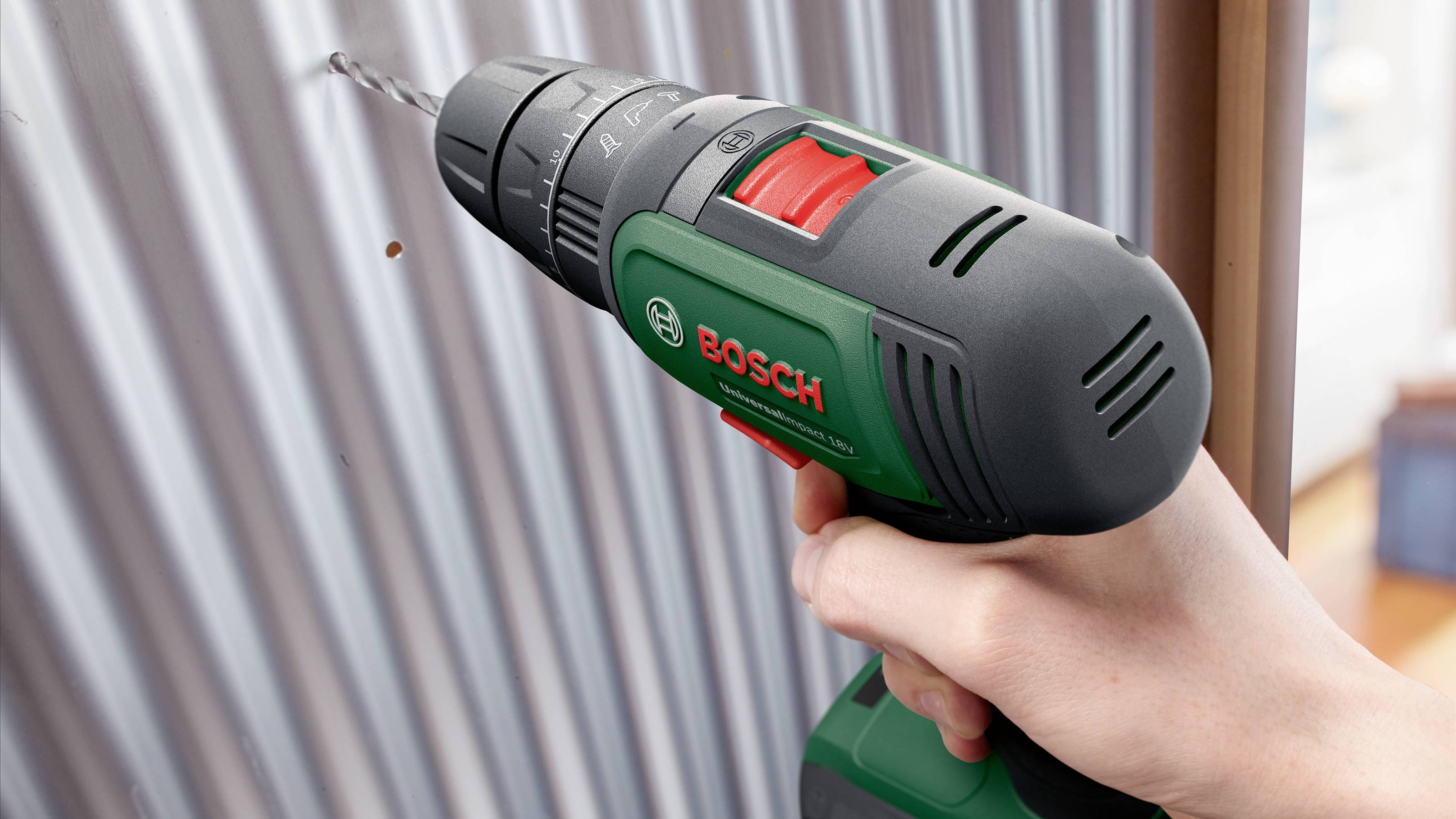 En person borrar ett hål i ett korrugerat plåttak med en Bosch sladdlös borr.