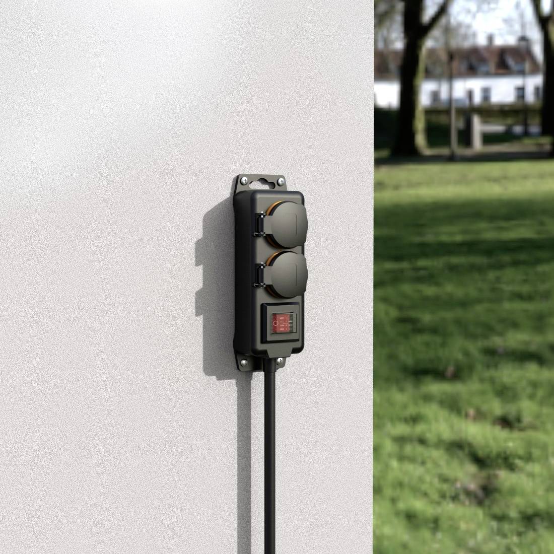 Utomhusuttag på en vägg med två platser och en röd strömbrytare. I bakgrunden gräsmatta och träd i dagsljus.