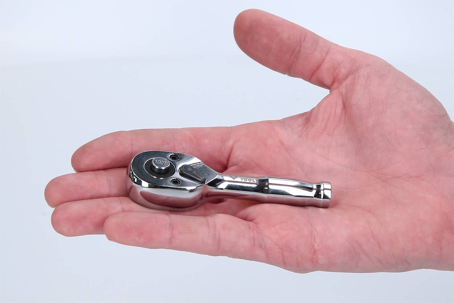 En hand håller en liten skrallnyckel, även känd som mini-skralle.