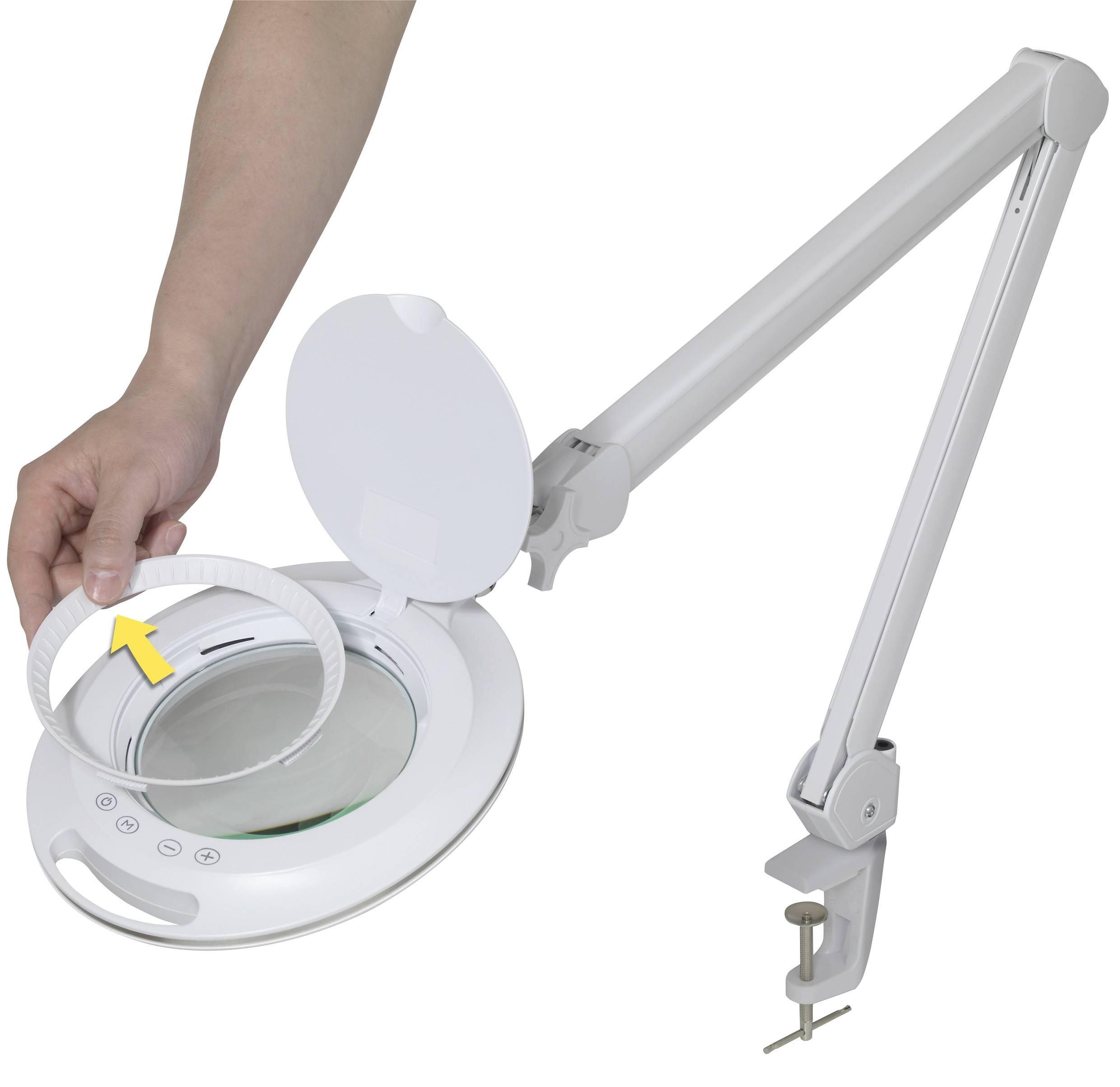 En hand tar bort den yttre ringen från ett vitt förstoringsglas med justerbar arm som är fäst vid ett bord.