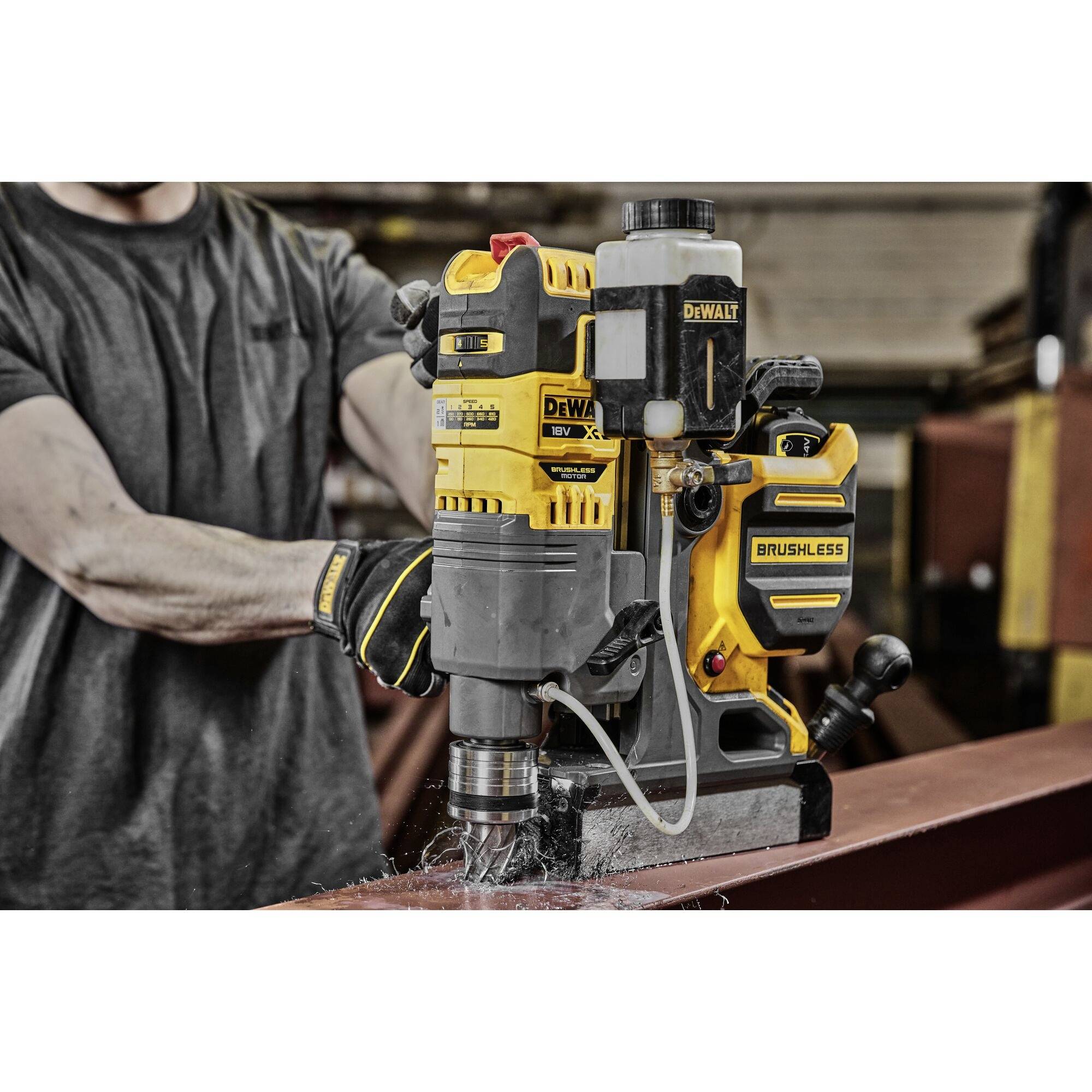 En person borrar med en magnetborrmaskin från DeWalt i en metallbalk i en verkstadsmiljö.