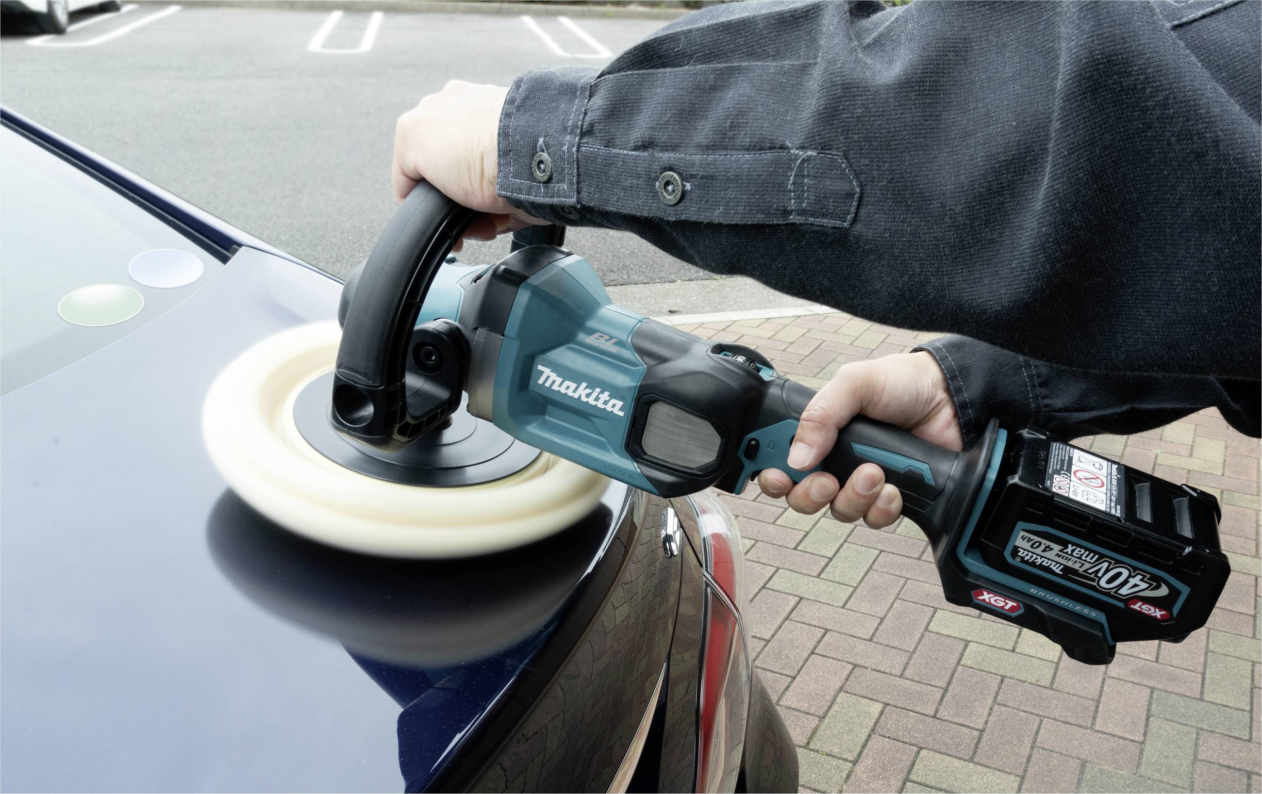 En person polerar ett biltak med en sladdlös polermaskin. Maskinen är blå och från märket Makita.