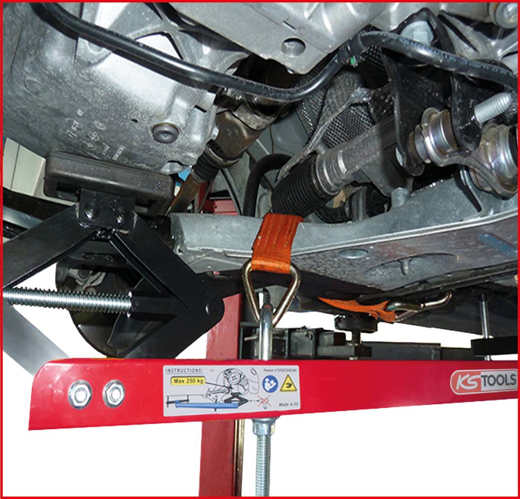 Undersidan av en bil som är säkrad på en lyftbocks ram. Ett orange spännband fixerar delar av motorn vid konstruktionen.