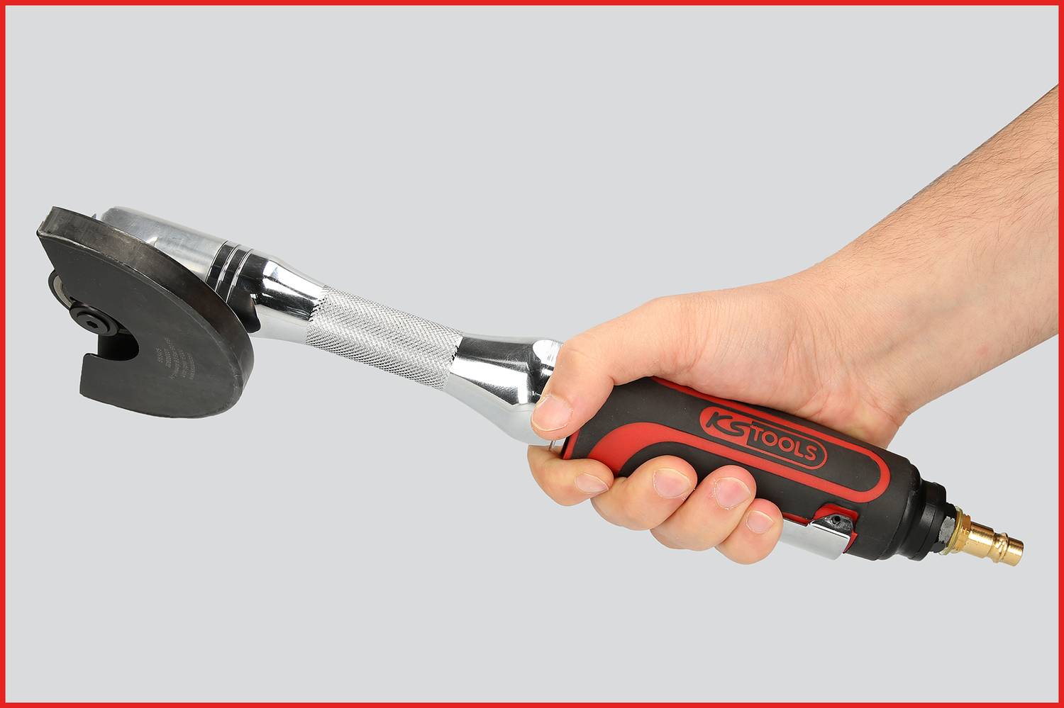 En hand håller ett pneumatiskt verktyg som liknar en vinkelslip. Det har ett rött och svart handtag med påskriften 'KS TOOLS'.