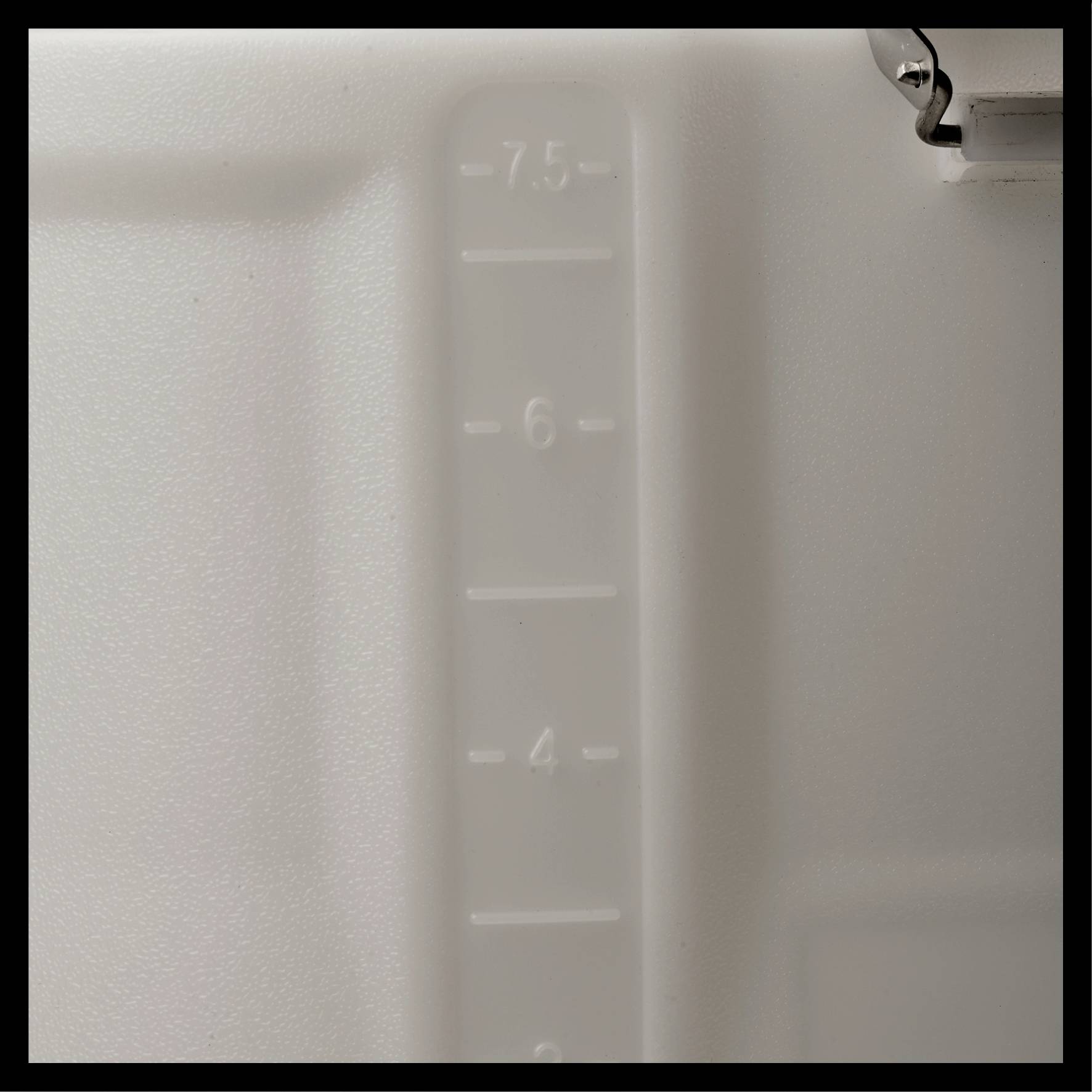 Närbild av en transparent behållare med skala från 1 till 7,5; visar volymmätning i milliliter.