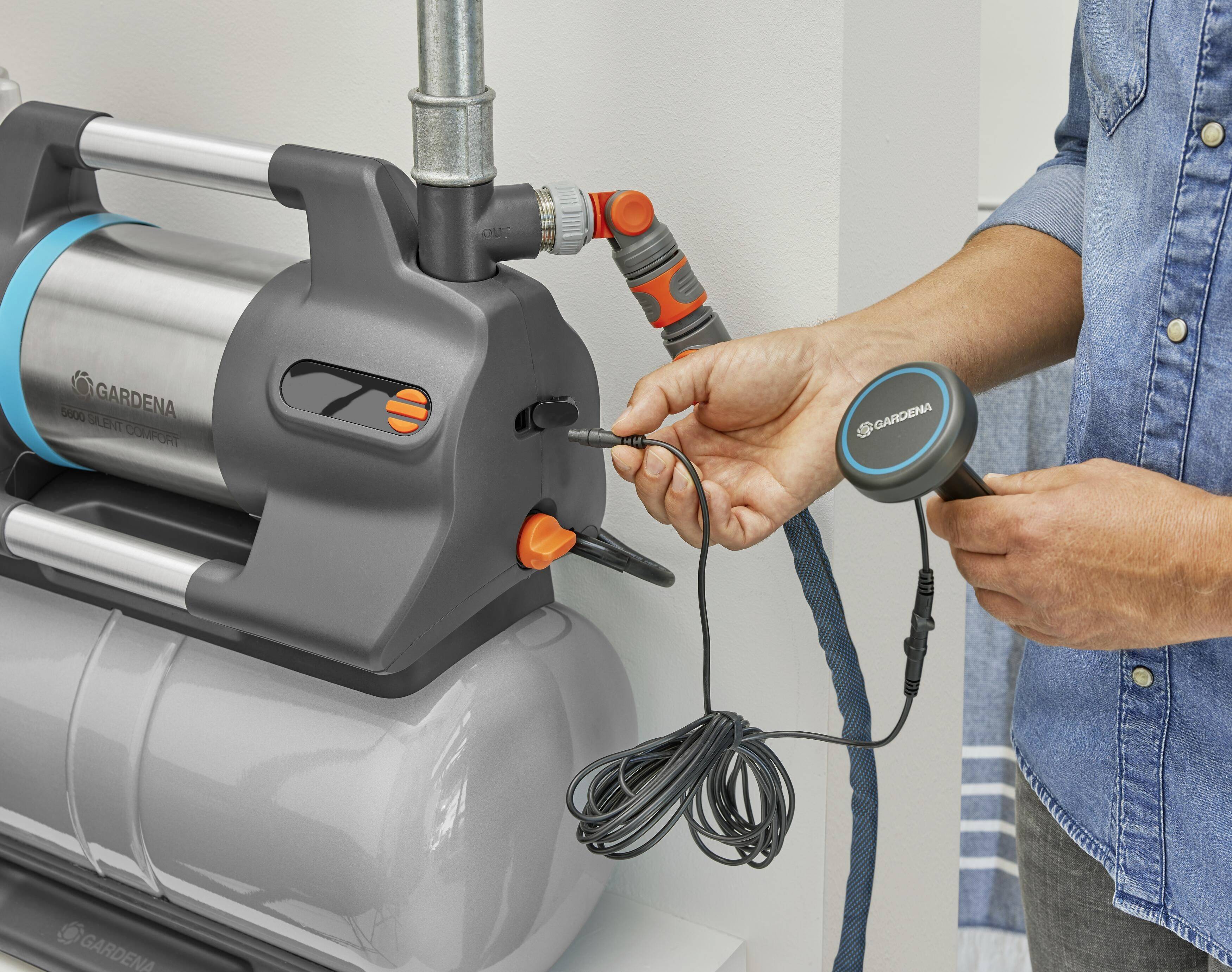 En person ansluter en sensor till en vattenpump. Pumpen har ett metallhölje och flera anslutningar.