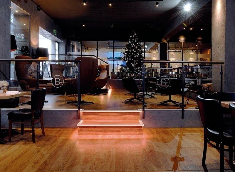 Ett stilfullt café med moderna möbler, julpyntat. En belyst gran står i bakgrunden.