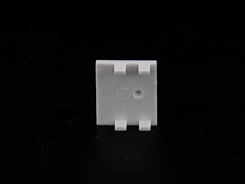 En liten vit plastfäste med flera clips framför en svart bakgrund.