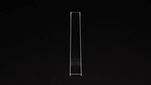 En enskild, smal, transparent glasstav står vertikalt framför en svart bakgrund.