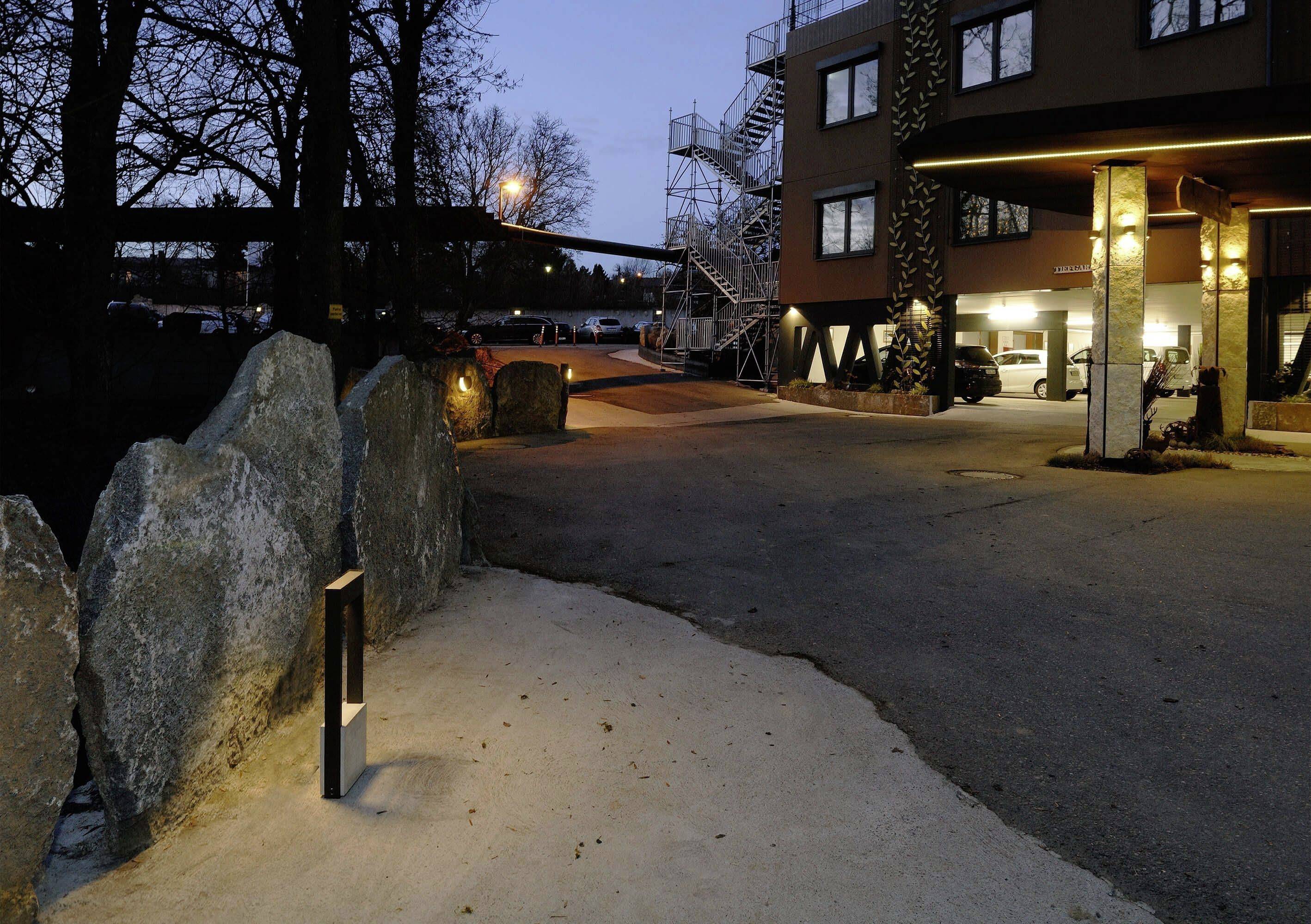 Tillgång till en byggnad vid skymning, upplysta stenplattor på en gång, modern arkitektur, trappa på byggnadens yttersida.