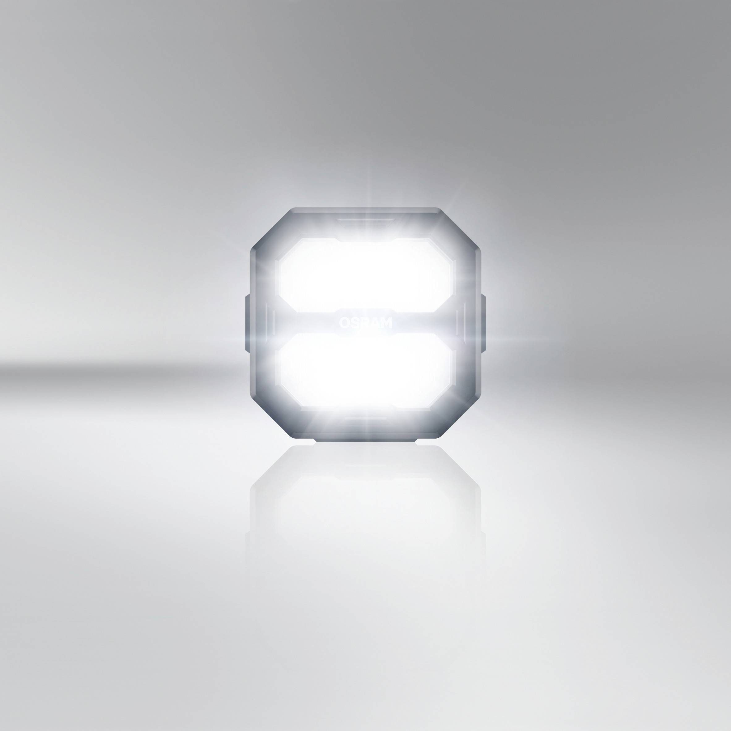Ett lysande, kvadratiskt ljus i ett neutralt rum som reflekteras på en slät yta.