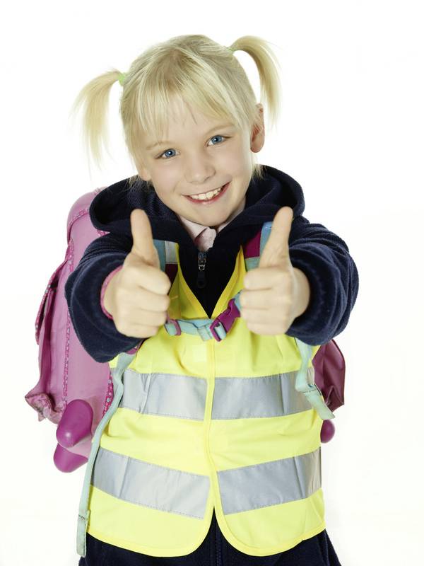 Ett blont barn ler och pekar upp med tummen på båda händerna. Det bär en gul varselväst och har en rosa ryggsäck.