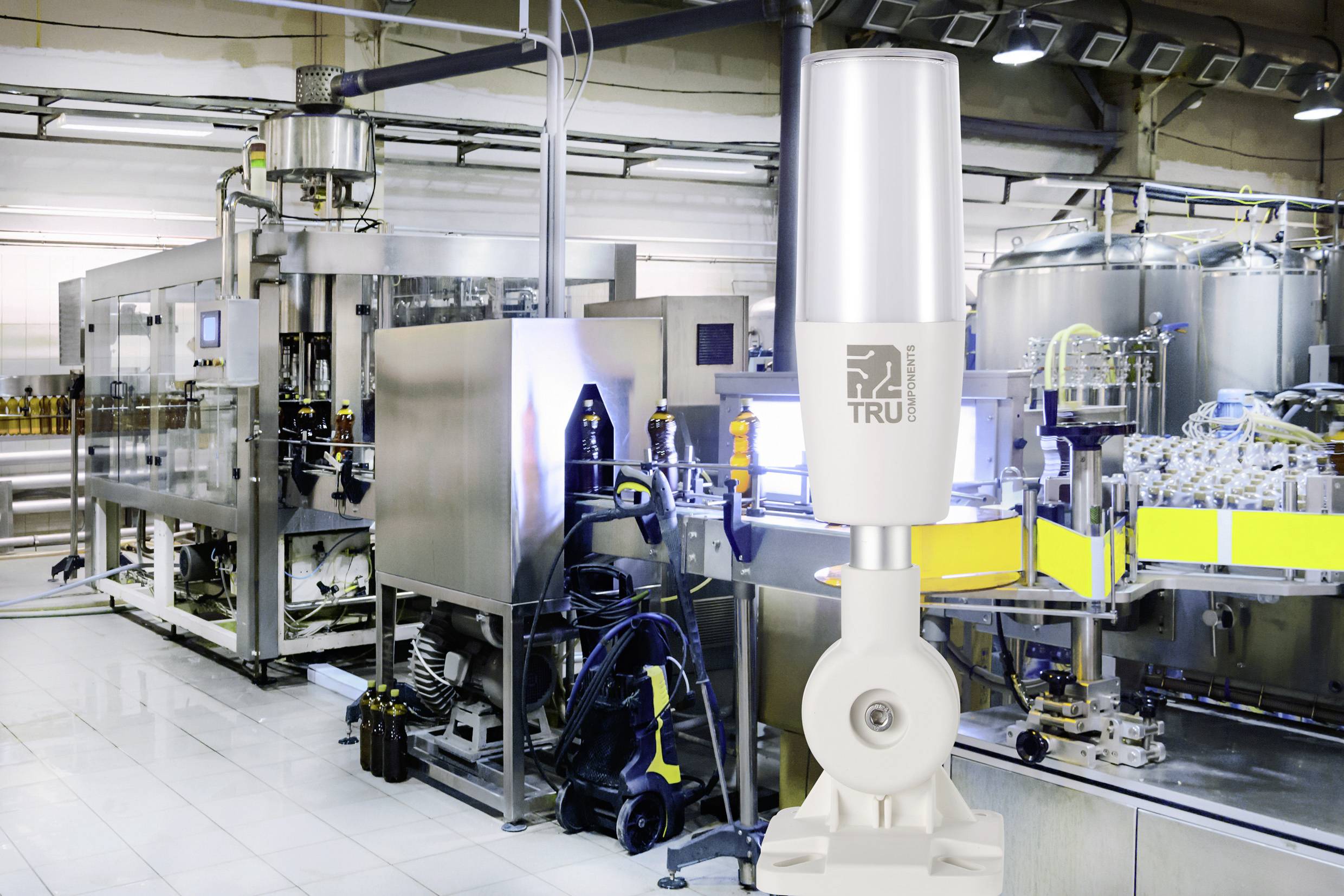 Produktionslinje i en modern fabrik med automatisk maskinanläggning. En stor, vit vakuumpump syns i förgrunden.