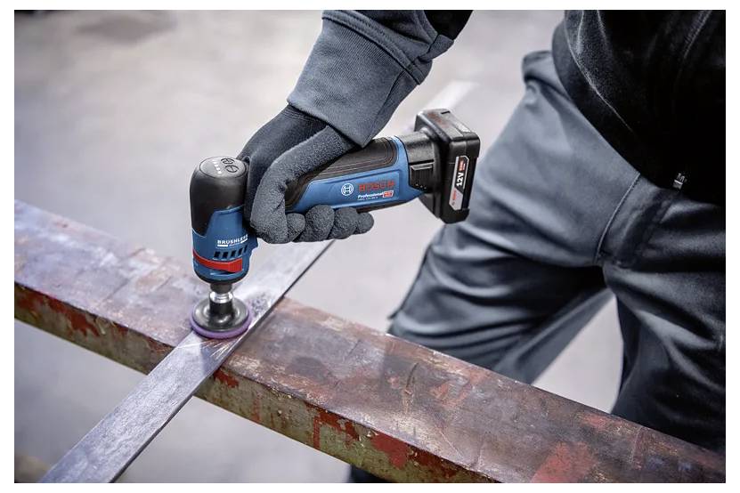 En arbetare med handskar använder en Bosch trådlös vinkelslipmaskin för att slipa rostigt metall på en stålbalk.