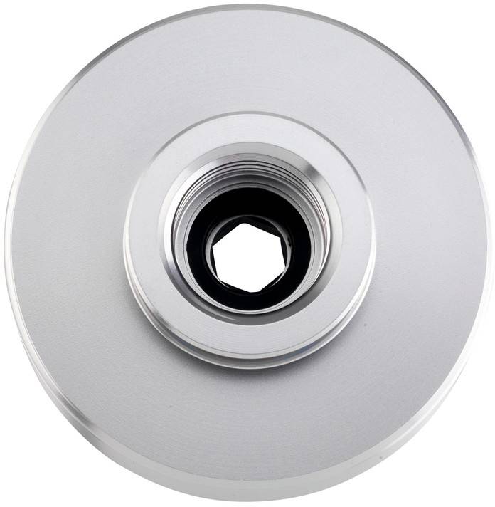 Närbild av en silverfärgad cirkulär metalldetalj med en central gängad öppning och sexkantigt inre hål.