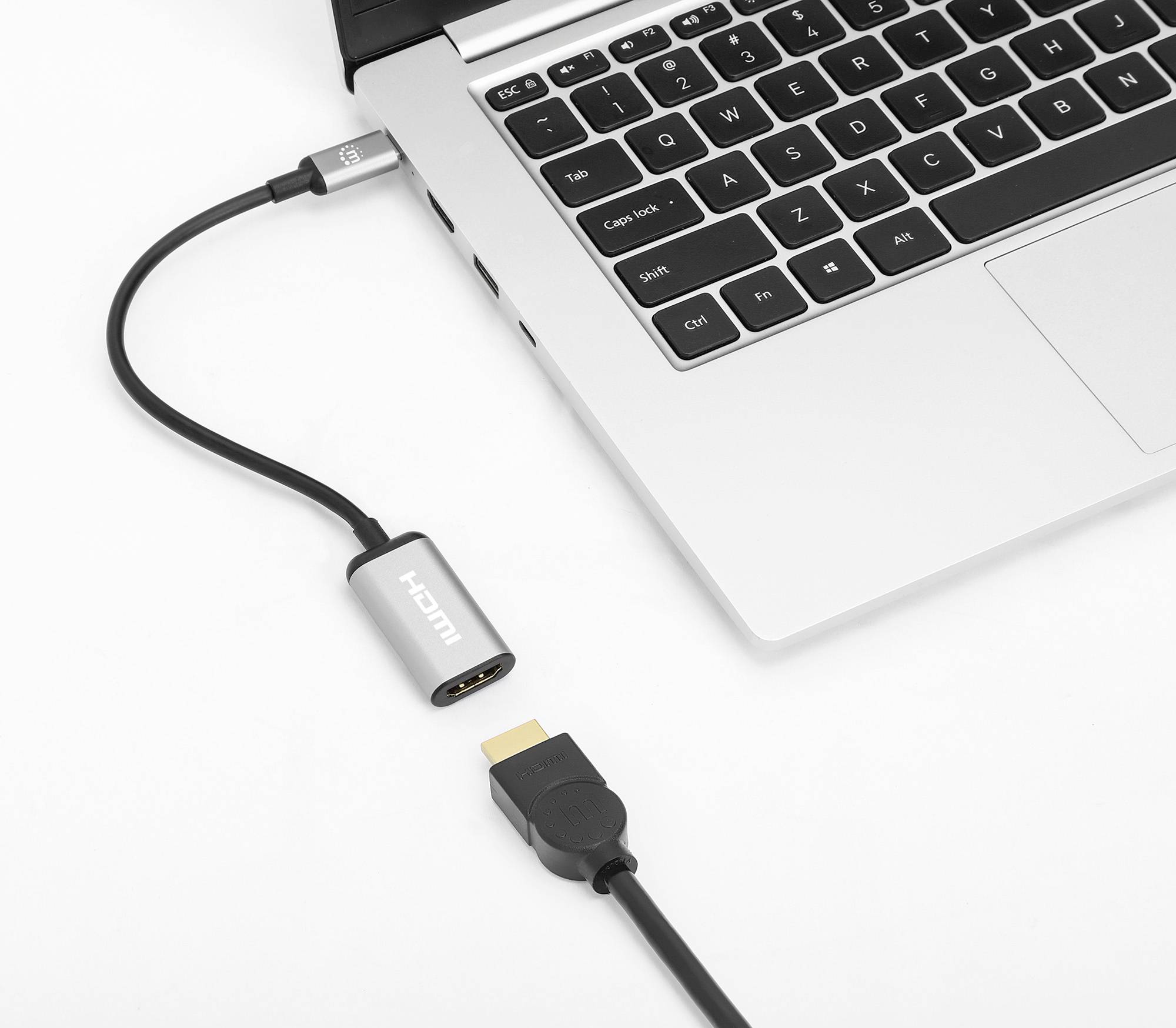 En HDMI-kabel ansluts till en bärbar dator via en adapter. Laptopen är delvis synlig och visar tangentbordet.