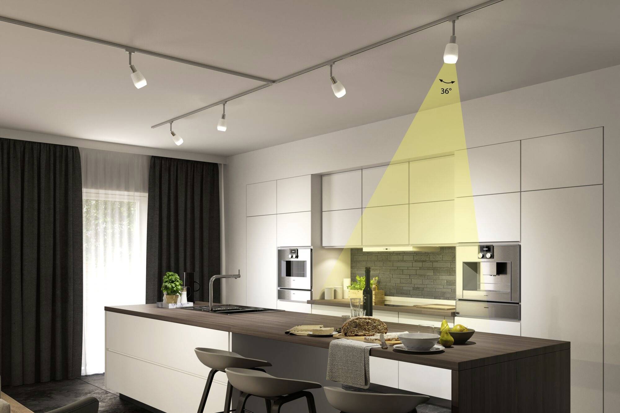 Modern kök med ö, vita skåp, dubbel ugn och LED-belysning. På bordet finns bröd, citroner och dekoration.