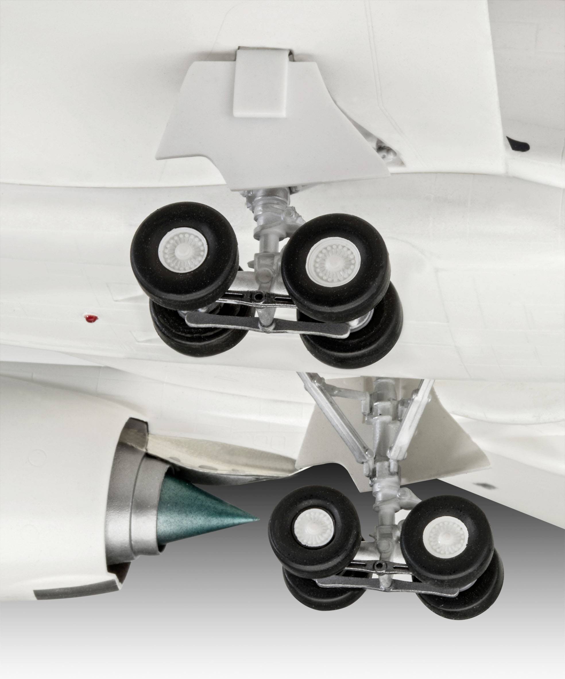 Närbild av ett flygplans landningsställ och motor under en vinge, visar tekniska detaljer av däck och landningsställets struktur.