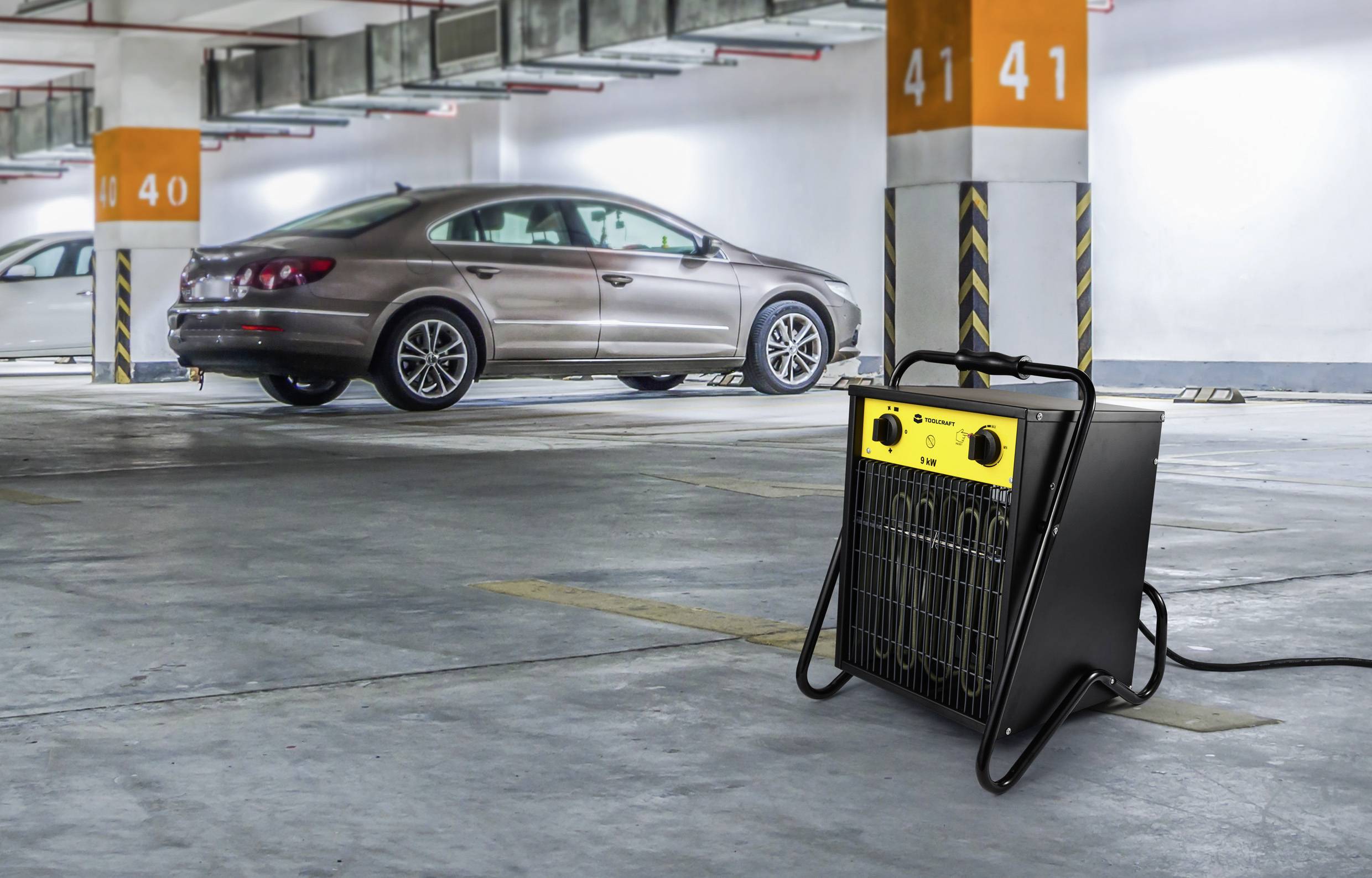 Parkeringsgarage med en bil och en elektrisk värmeanordning i förgrunden.
