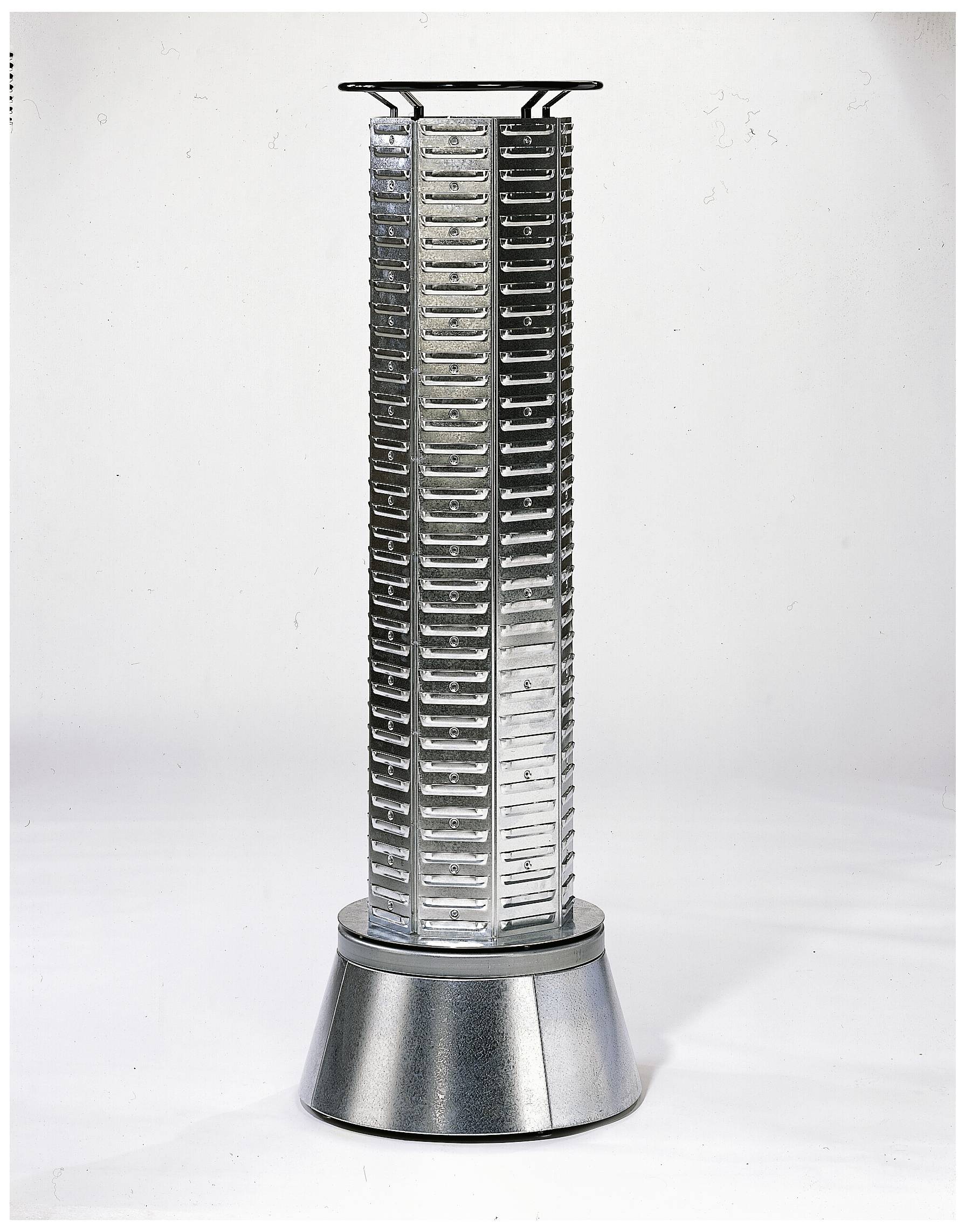 En silverfärgad, cylindrisk torn med flera springor på en metallisk, konisk sockel. Vetenskapligt-tekniskt design.