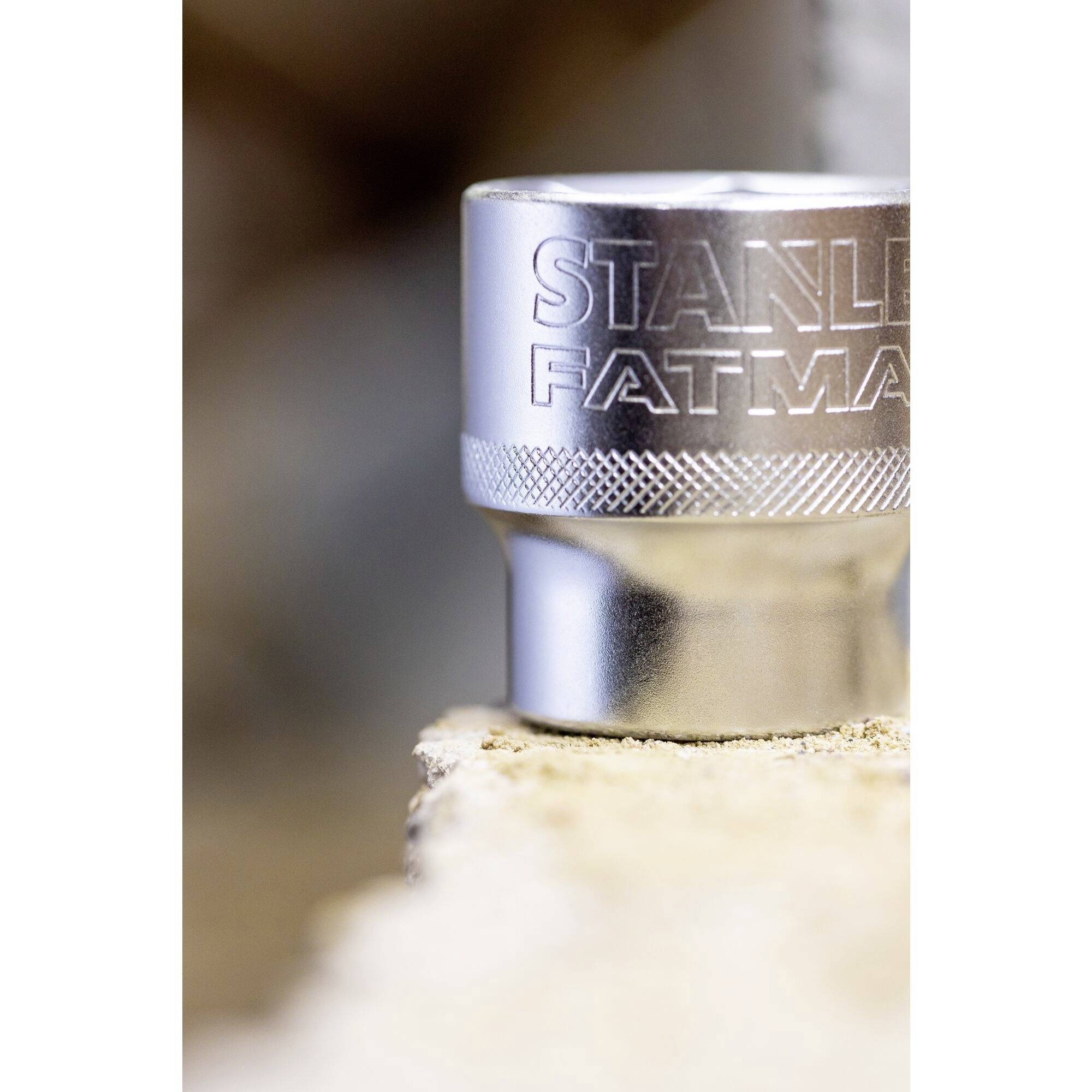 Närbild av en silverfärgad skiftnyckel med gravyren 'STANLEY FATMAX' som står på en oskarp, träliknande bakgrund.