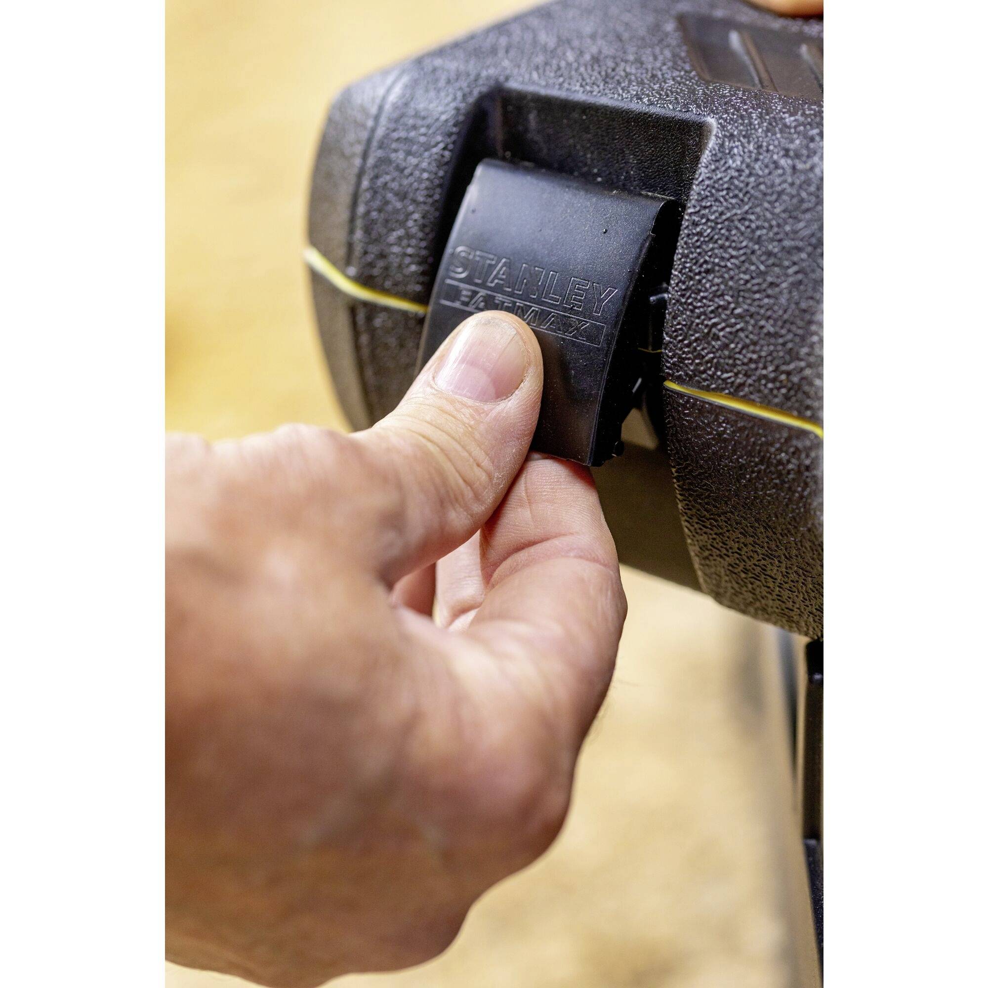 En hand öppnar ett lås på ett svart fodral som bär logotypen 'STANLEY'.