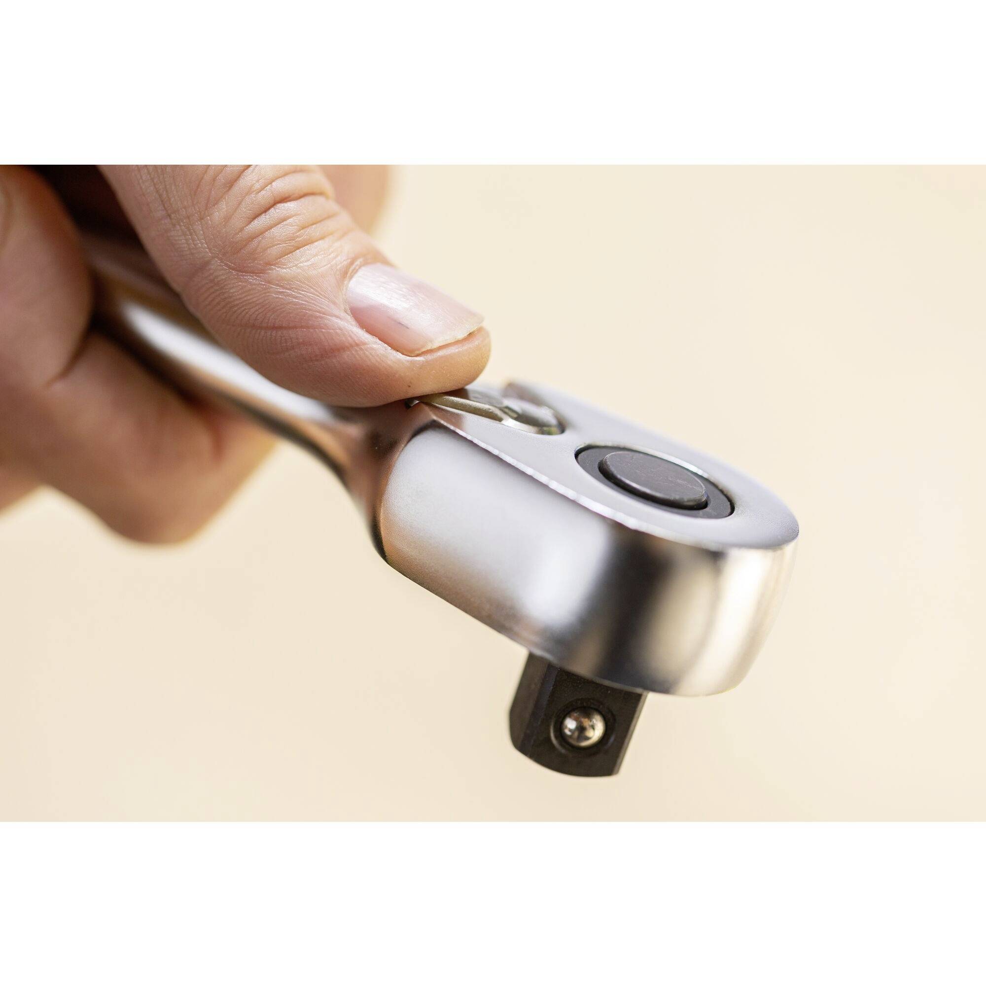 En hand håller en glänsande kromskiftnyckel med ett svart handtag, redo att användas.