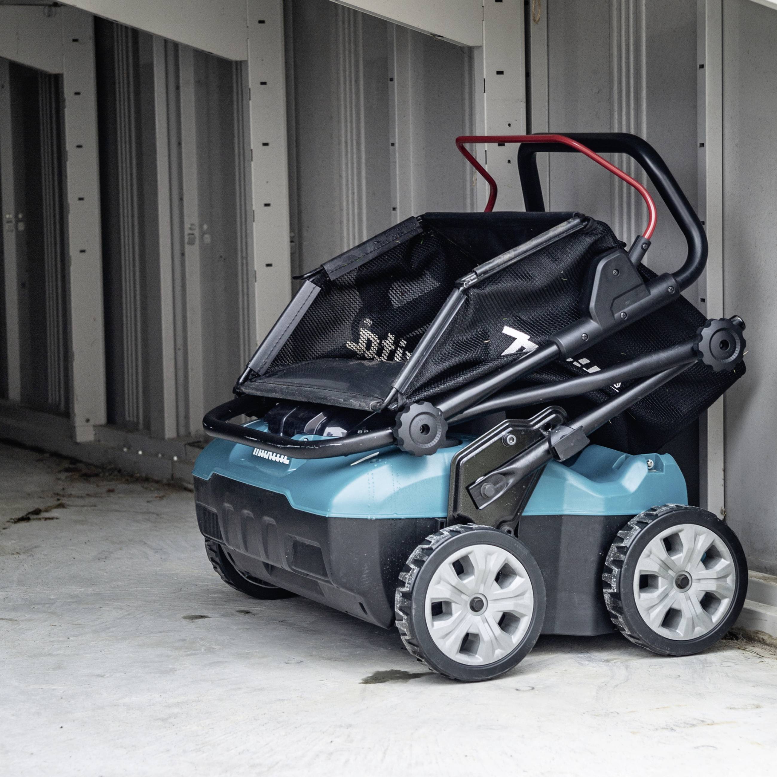 En ihopvikt blå och svart barnvagn står i ett garage.