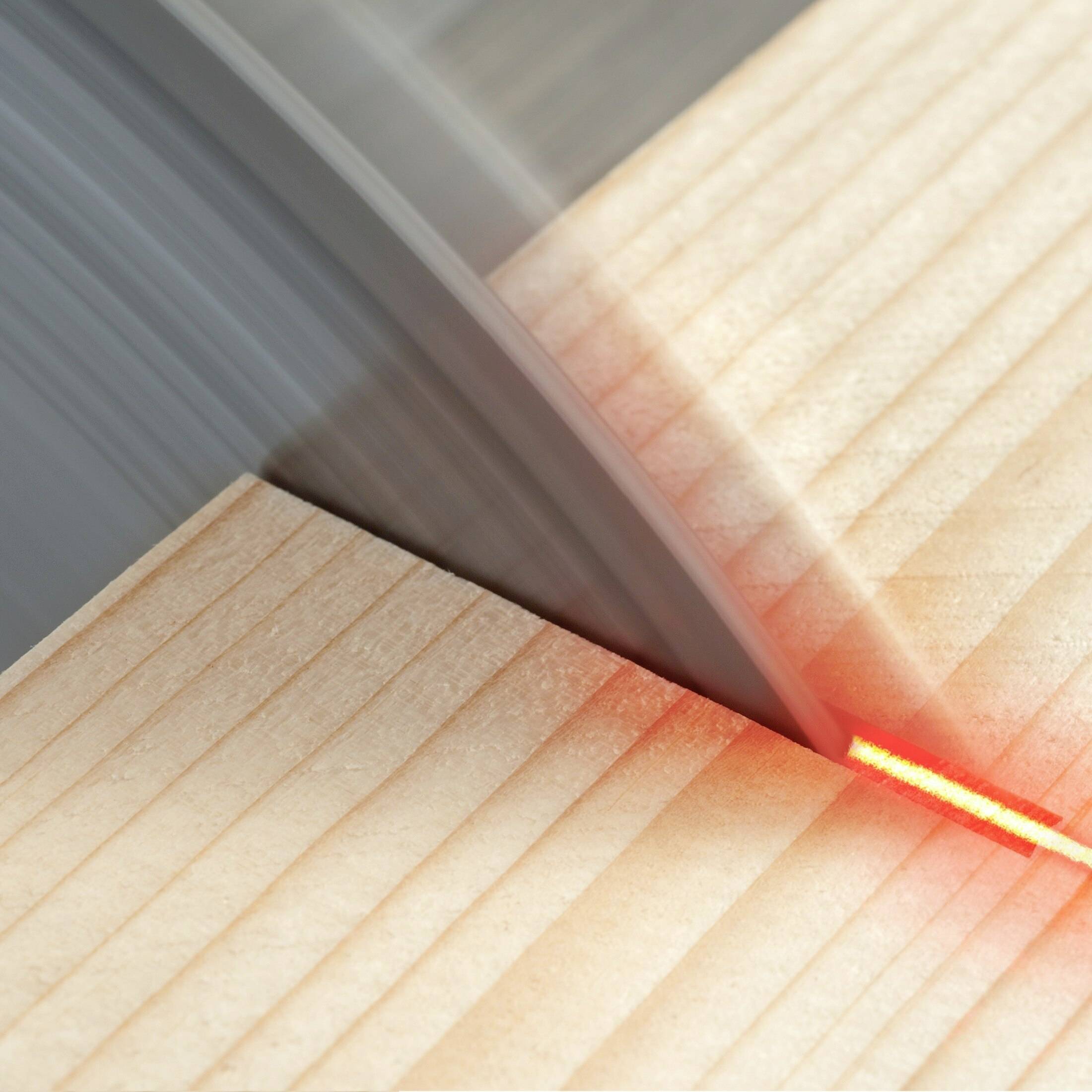 Cirkelsågen sågar ett träbräde, en röd laser markerar skärlinjen för att säkerställa ett exakt sågningsmoment.