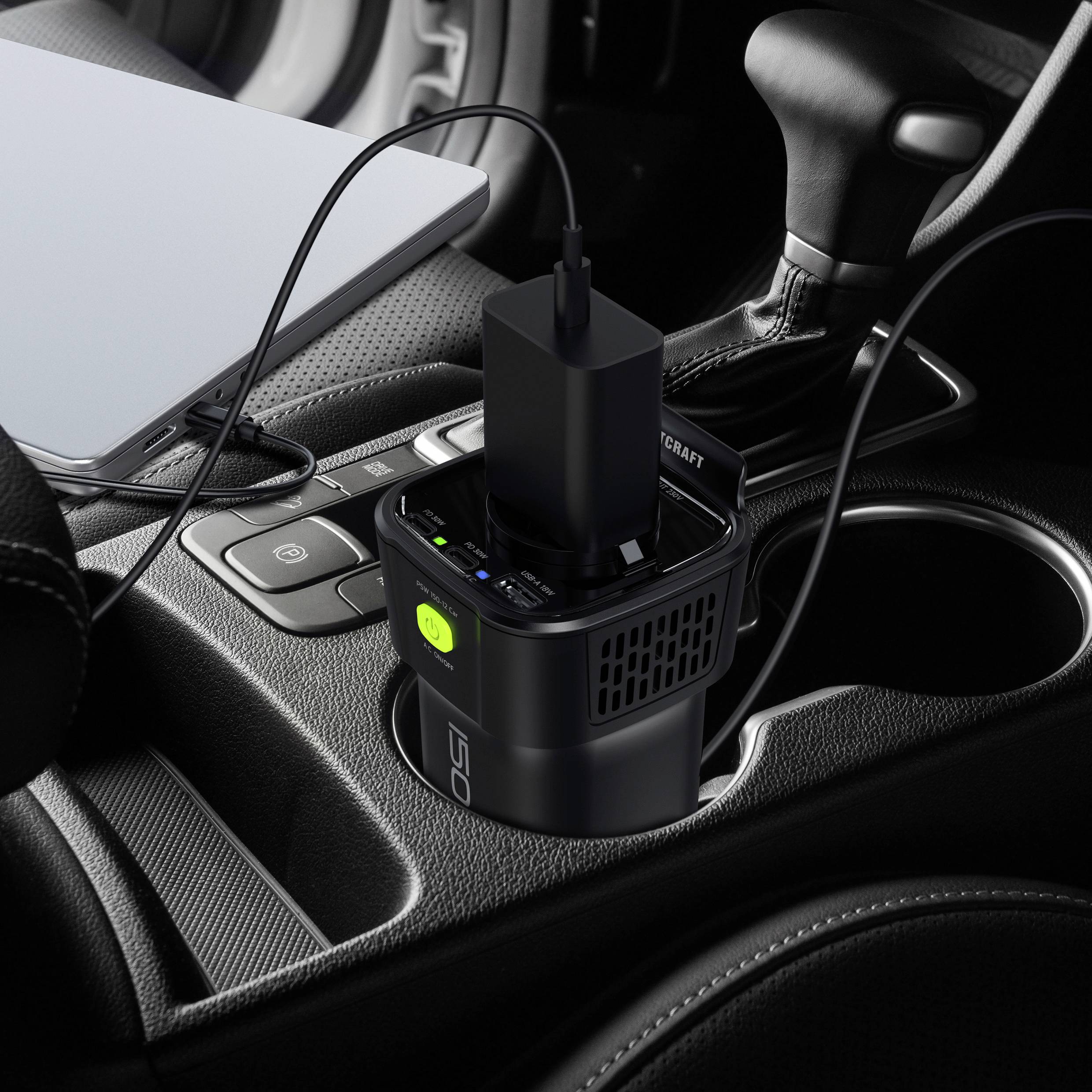 Bärbar laddningsstation på en bilkonsol, laddar en bärbar dator. Adapter är inkopplad, USB-kabel ansluten. Enheten visar grön LED.