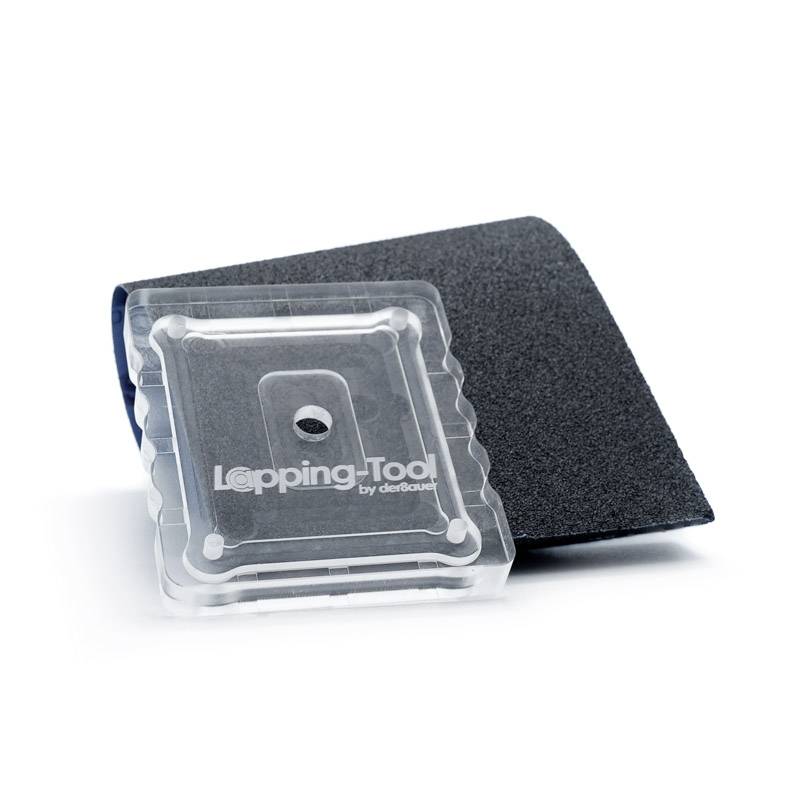 Slipverktyg på slippapper, använt för ytbehandling. Transparent plastlåda ligger på mörkt papper.