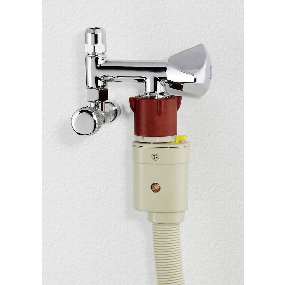 Krom vattenkran med röd-vit universaladapter och ansluten slang, monterad på vit vägg.